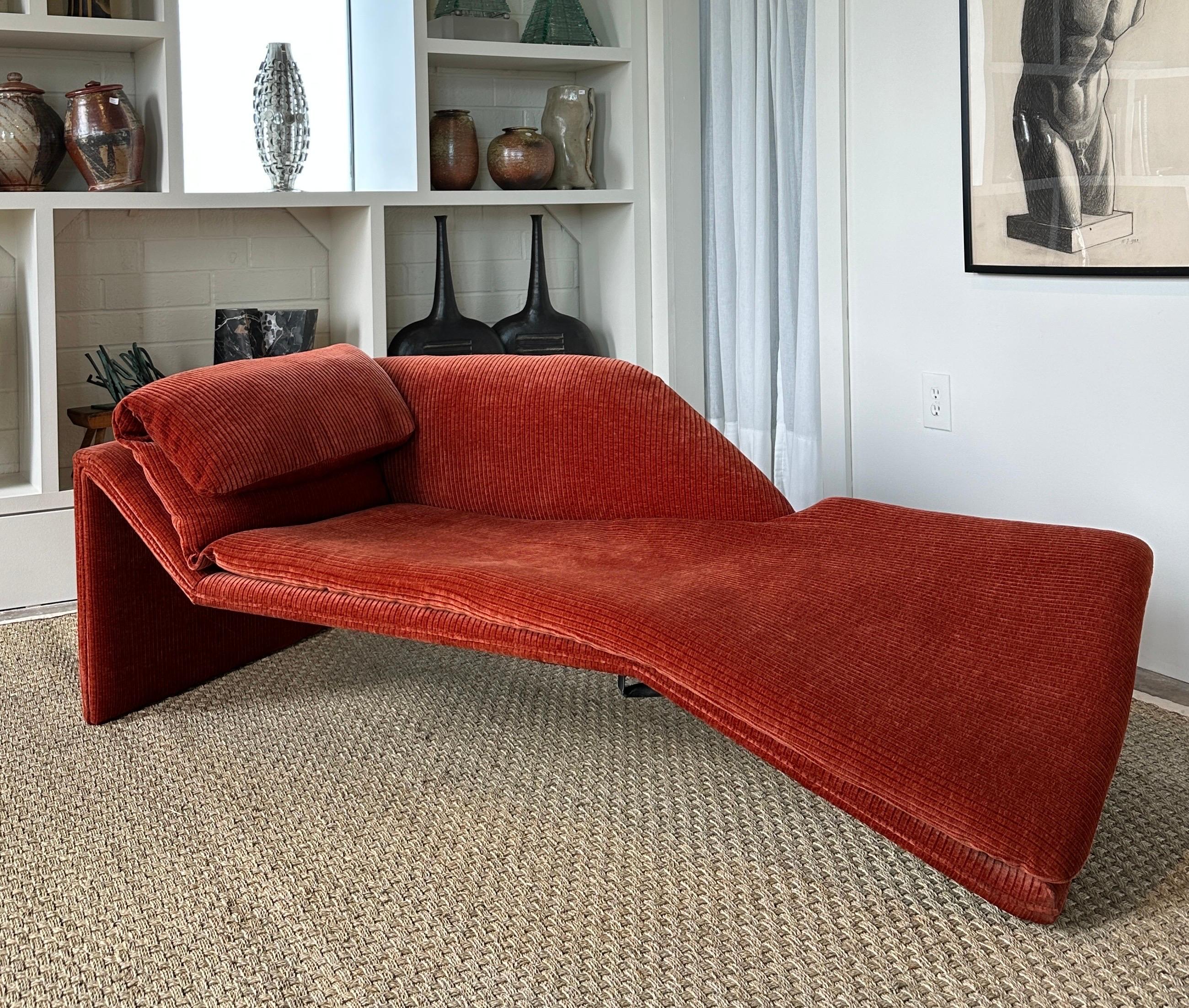 Una chaise molto scultorea dal design asimmetrico, bella da tutte le angolazioni e molto comoda. Tessuto a coste color cannella/ruggine con una texture ricca di colore. 
Le pieghe ispirate agli origami della struttura e del cuscino superiore creano