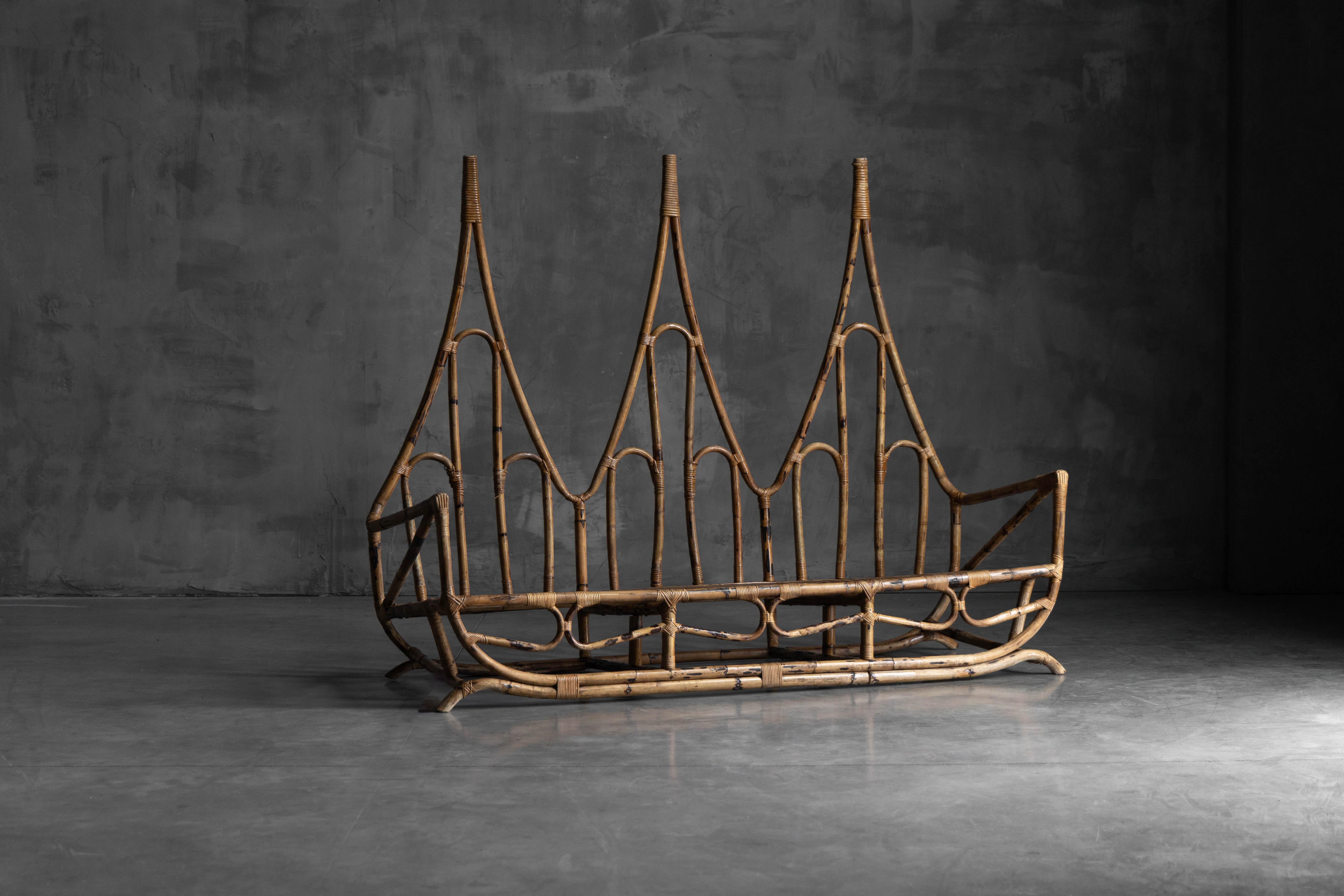 Sculptural bamboo three-seater bench, designed in Italy in the mid-20th century, showcasing a rare and expressive silhouette with a soaring, architectural backrest. Hand-shaped bamboo rods and meticulously bound rattan joints define the bench’s