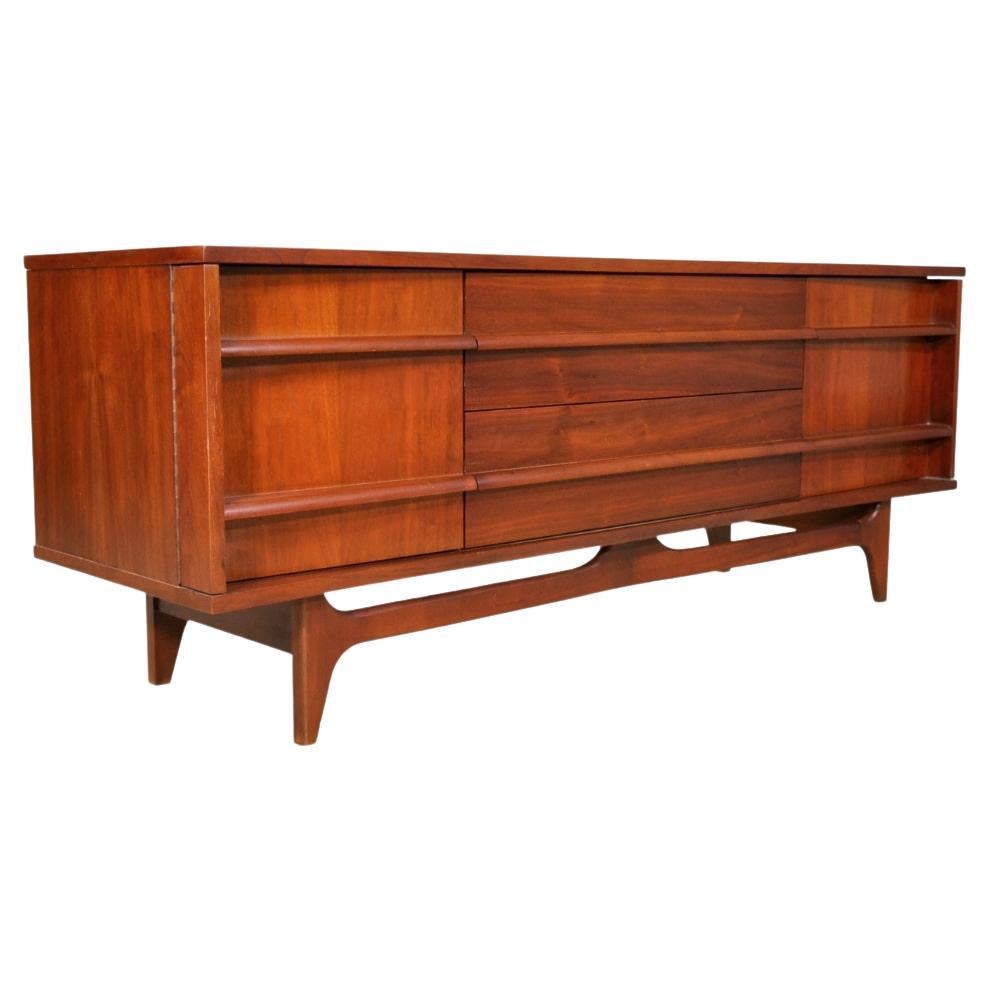 Modernist server featuring two doors and three drawers. Handsome bow front with angled drawer pulls that run the length of piece. Wonderful walnut wood graining. Perfect height for a media console!