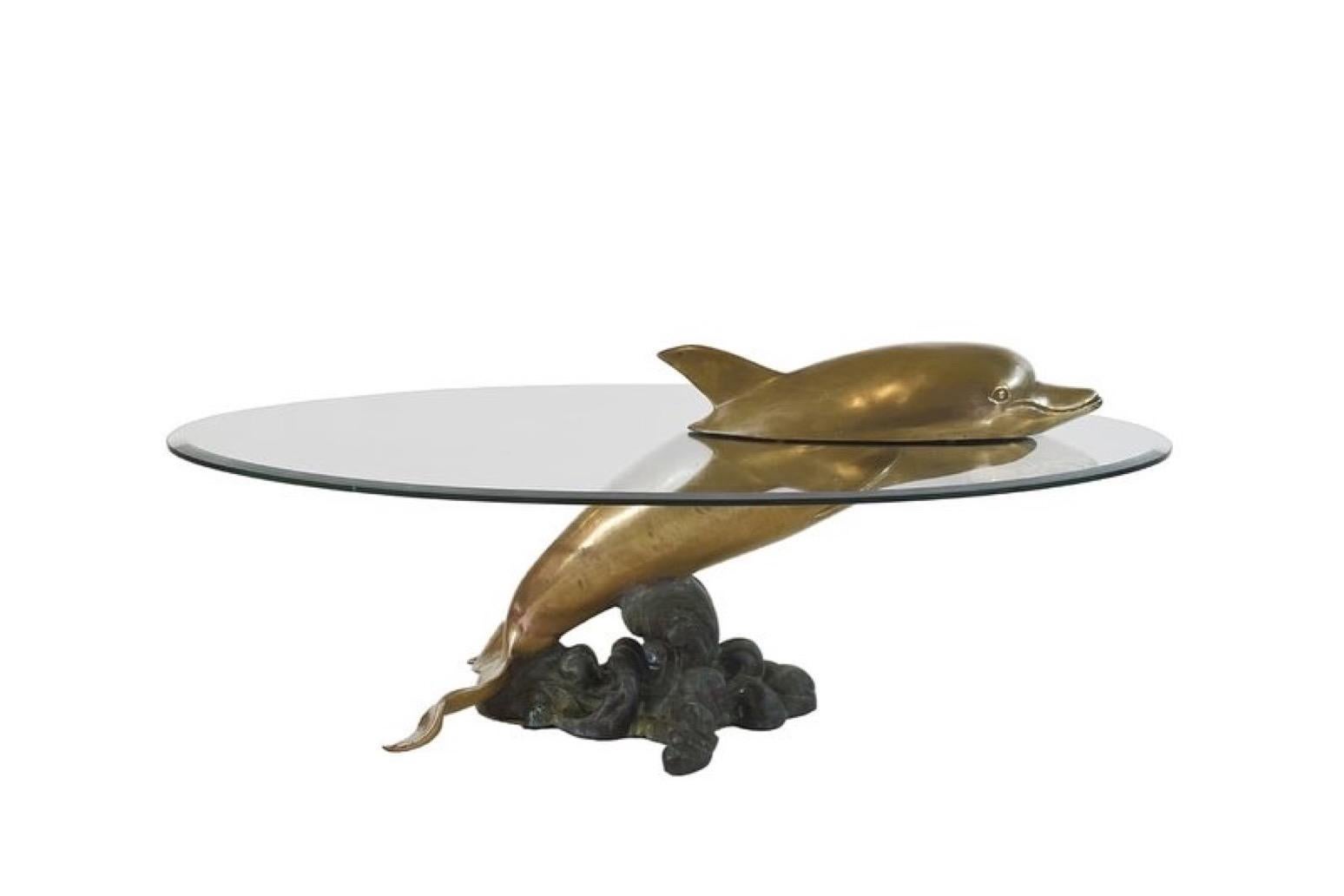 A truly eye catching, unusual Brass metal table, fashioned in the shape of a Dolphin on an elegant Brass ‘Ocean Wave’ base and with a Glass top. The Tabletop comes in matching facet Glass. The head of the Dolphin lies on the glass top and makes it