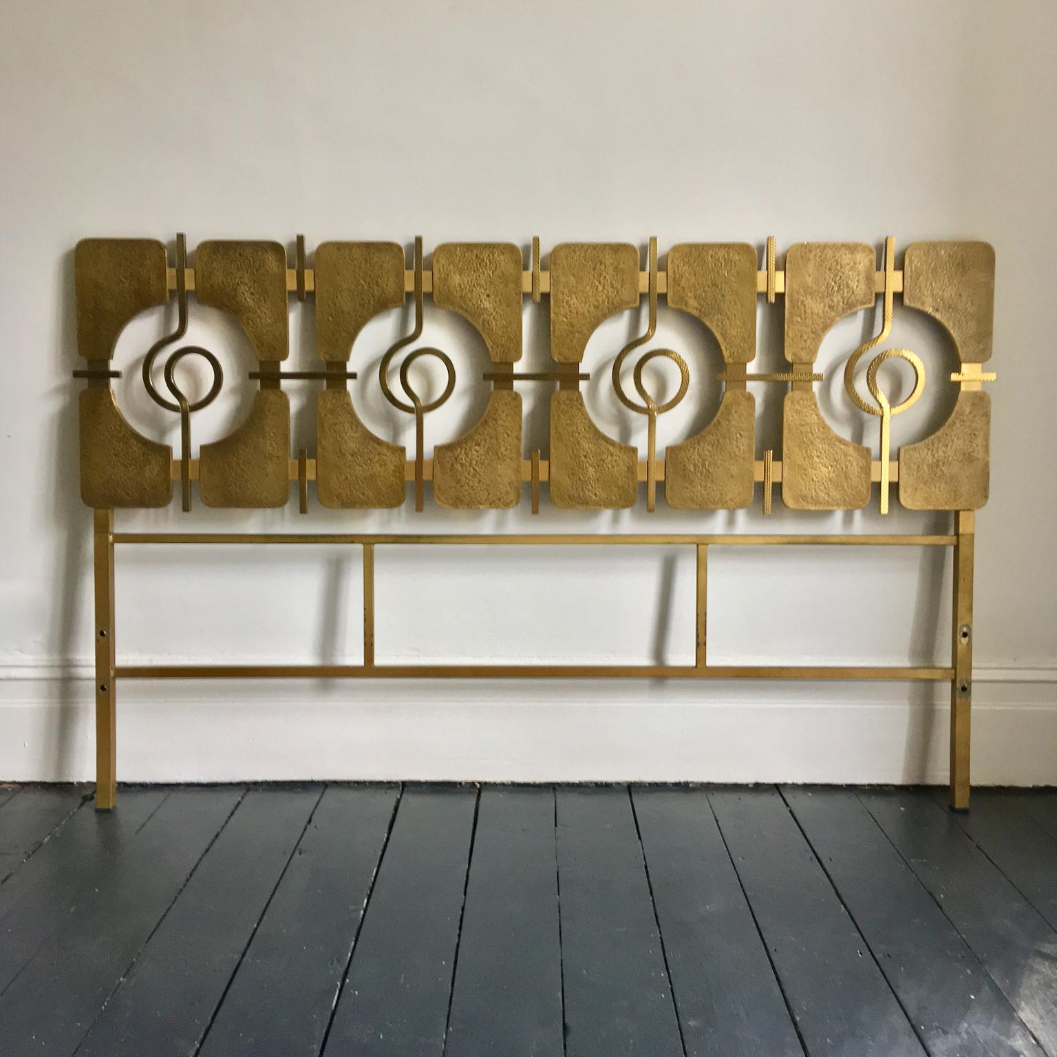 Striking sculptural headboard of cast brass on a gold-colored frame, designed by Luciano Frigerio, Italy, circa 1965. 

This is a stylish, and heavy piece, in good original condition. The decorative section comprises panels and linking scrolls of