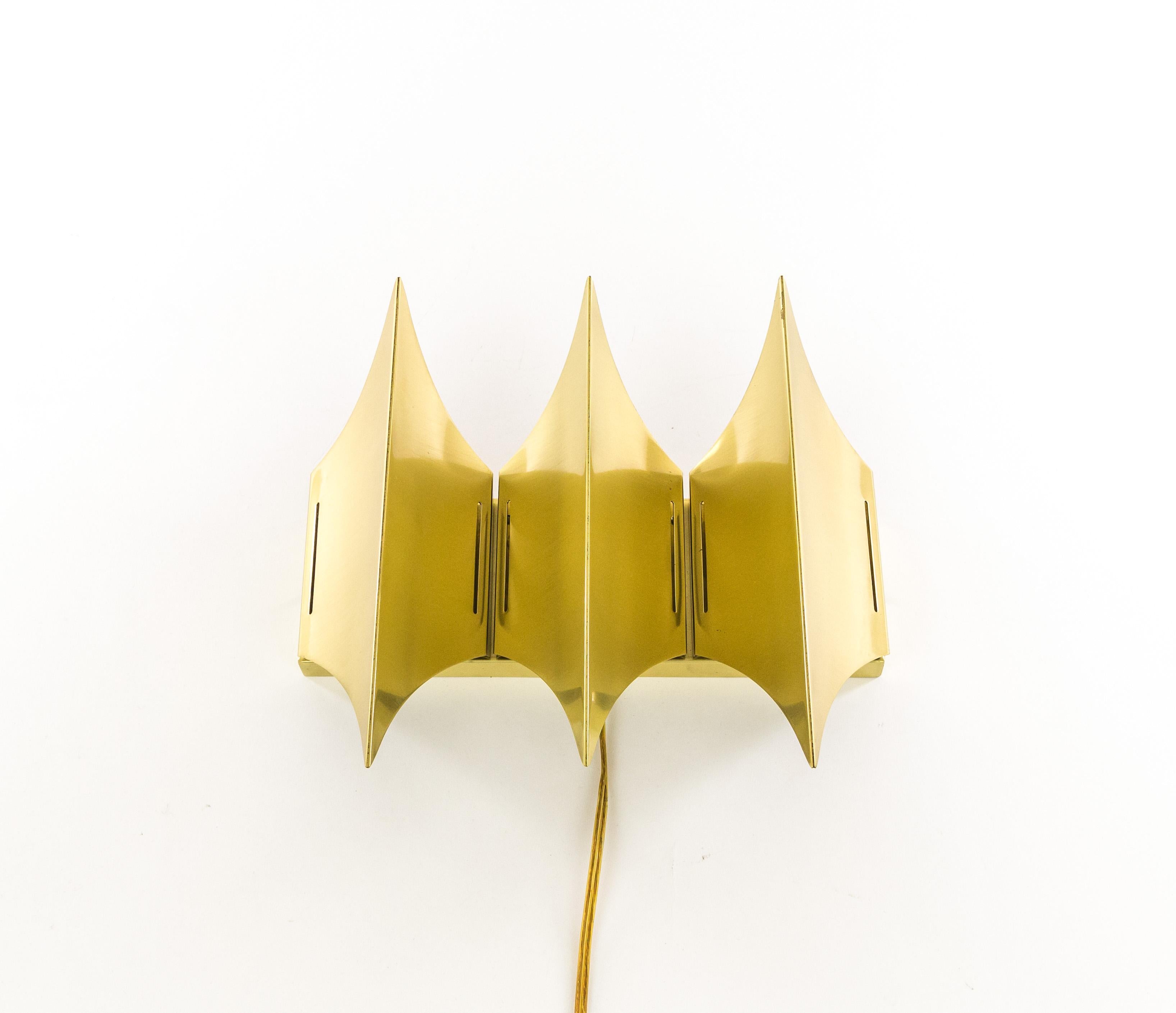 Sculptural wall lamp Gothic III produced by Danish lighting company Lyfa, with three-light sources. The lamp has been designed and manufactured halfway the 1960s. This lamp is made of brushed solid brass that accentuates the three horizontal