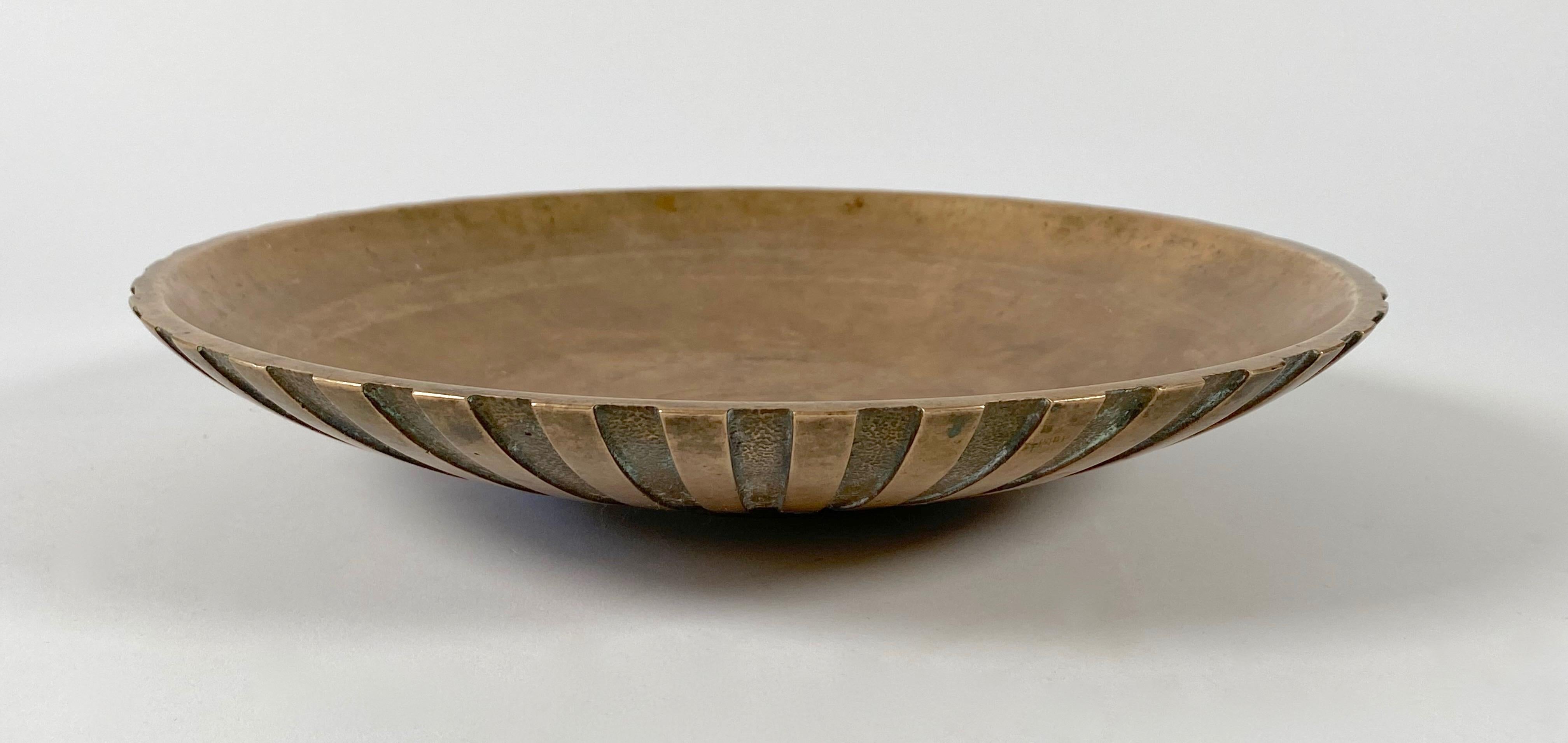 Bronze bowl by Tino's of Denmark, with an expanse of radial lines emanating from the bottom center creating a sunburst effect, deeply grooved with a textural element adjacent running in parallel. The bowl is created out of solid bronze and has much