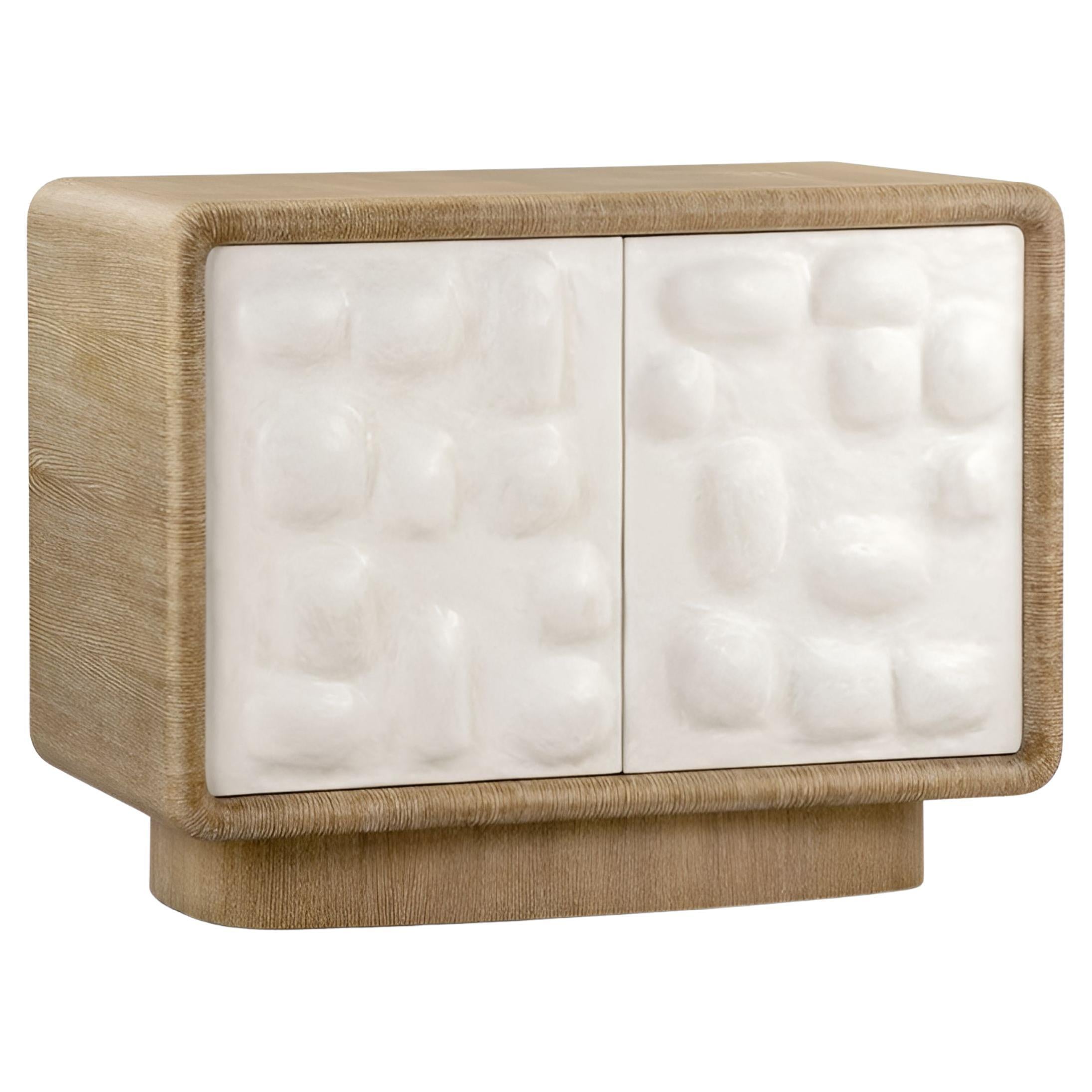 Este elegante armario de dos puertas está fabricado en madera de roble, con un sofisticado acabado cerámico que resalta su veteado natural con un bello efecto encalado. Las puertas son especialmente distintivas, ya que presentan una textura enlucida
