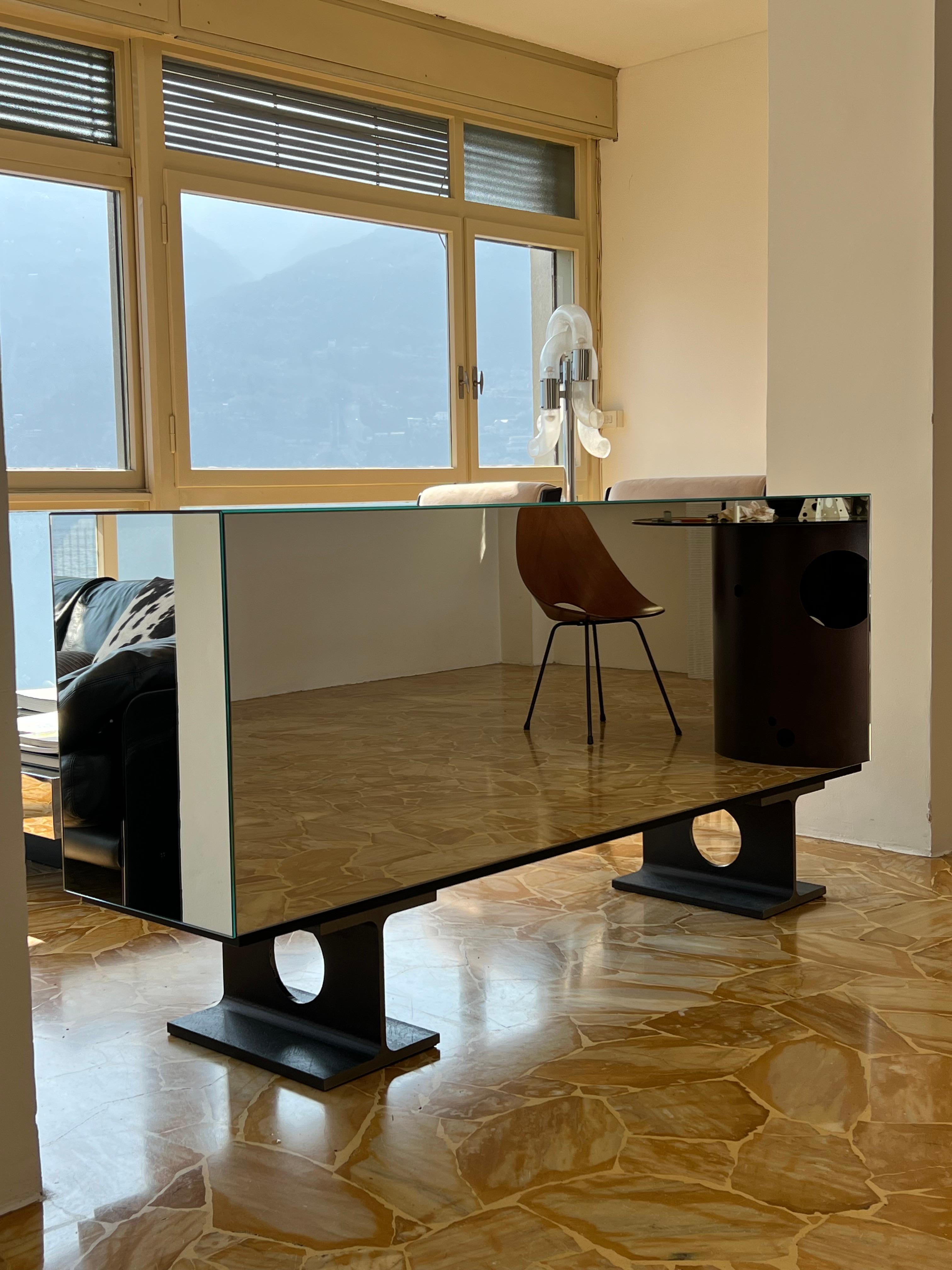 Conçu par Spinzi , Milan est un buffet-credenza recouvert de miroirs qui invite à réfléchir à ce qui est nécessaire et à ce qui n'est pas nécessaire. La correspondance entre les poutres solides et les miroirs évanescents est une image parfaite de la