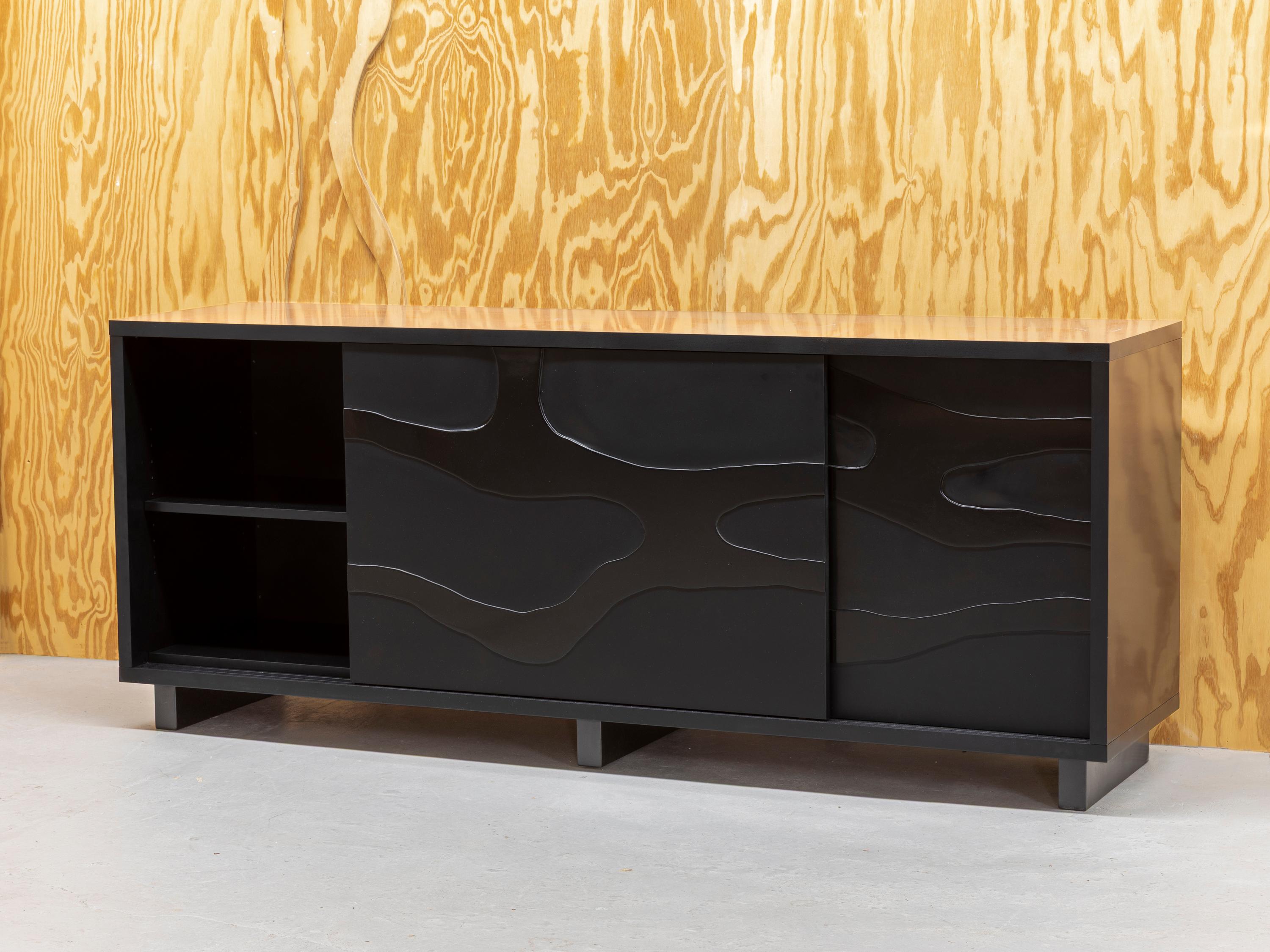 This sideboard by Jacques Jarrige features sliding doors adorned with a sculptural relief that evokes the gentle, meandering flow of a river. Carved in rhythmic, fluid lines, the surface captures the quiet movement of water—subtle yet alive—infusing