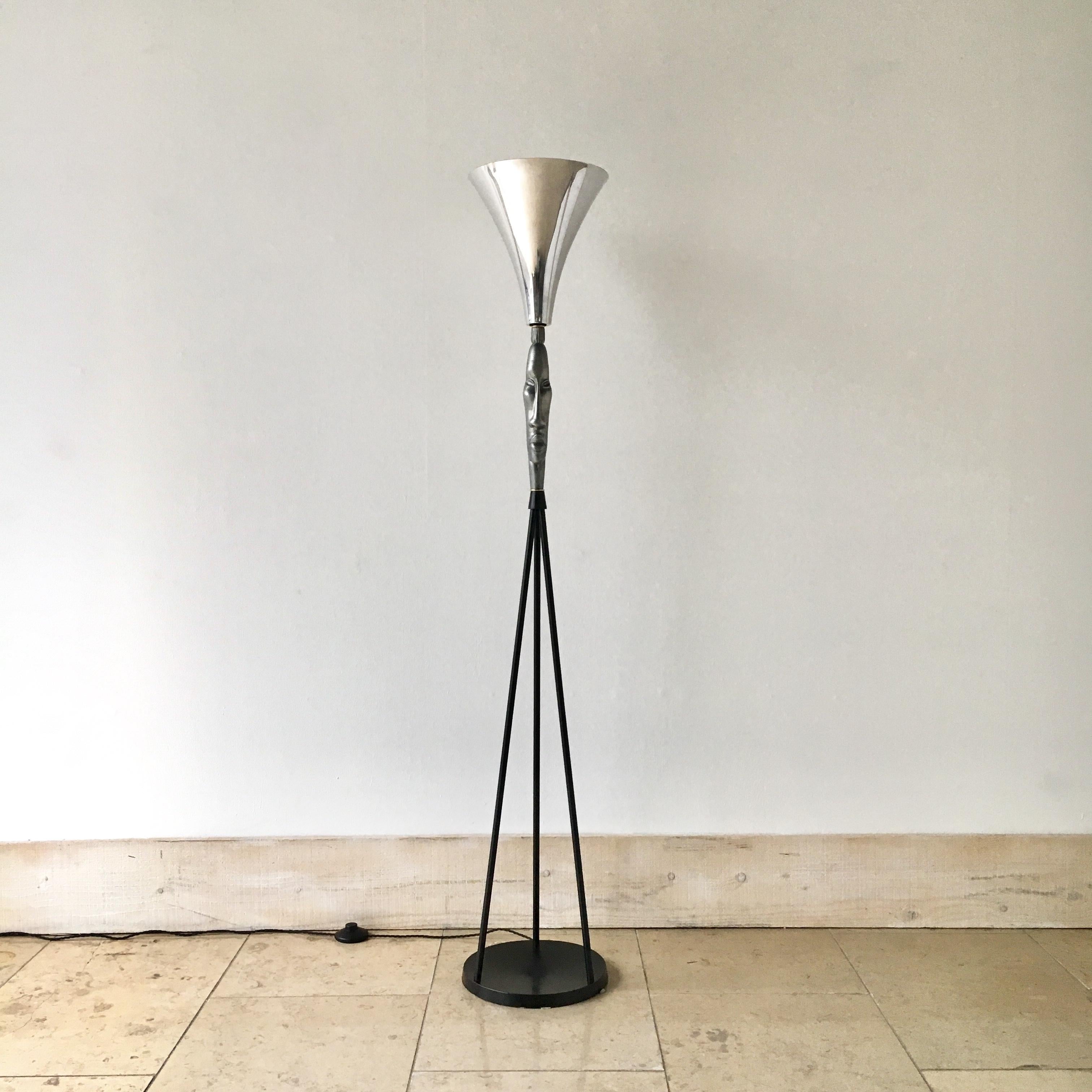 Sculptural cast aluminium uplighter floor lamp with Tiki face set on a blackened steel rod tripod base with polished aluminium shade, 1940s.

Refurbished and rewired to UK standards.