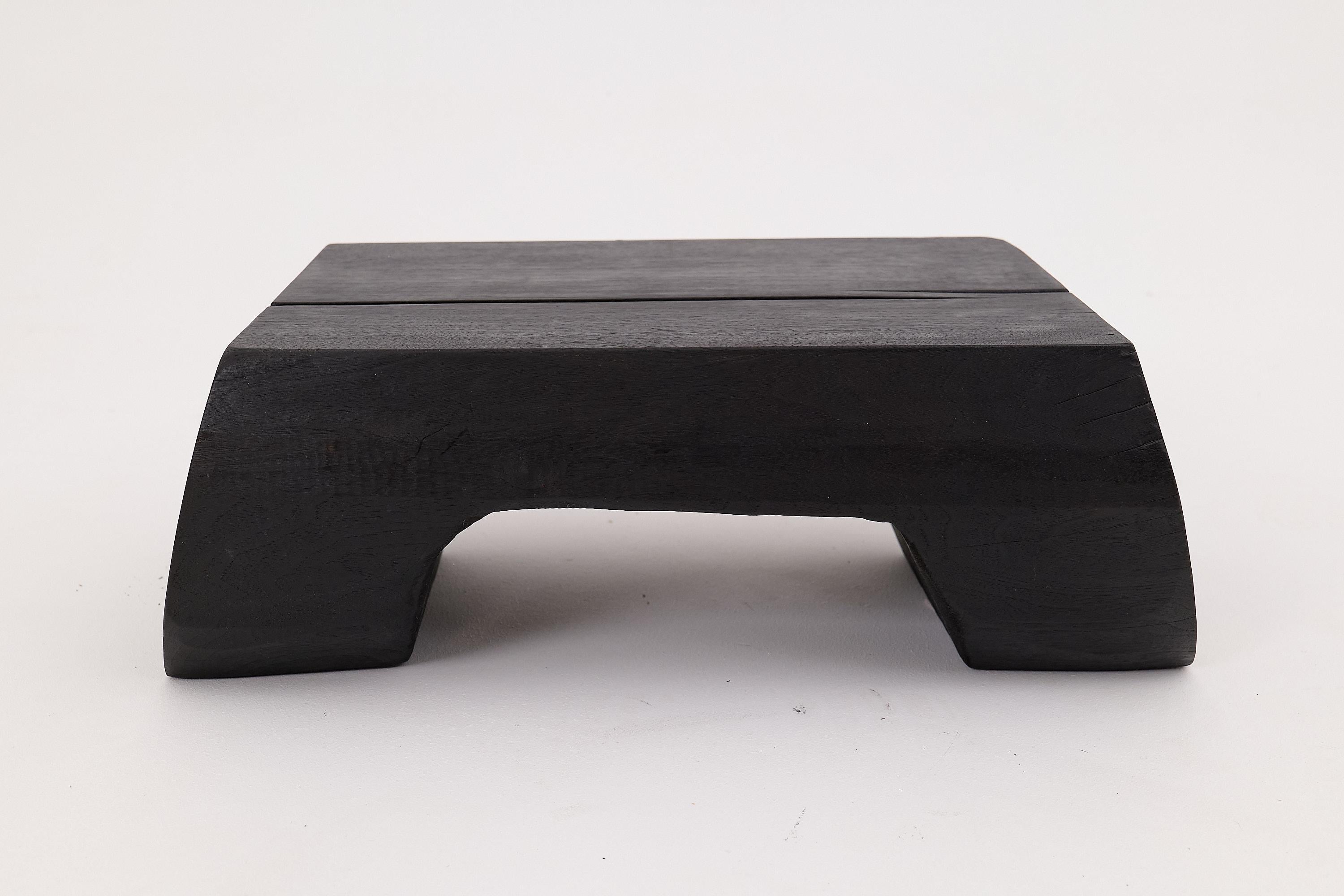 This low sculptural table commands attention through its quiet strength and architectural clarity. Hand-carved from a single block of solid reclaimed hardwood, it features a deeply charred finish that accentuates the grain while preserving the
