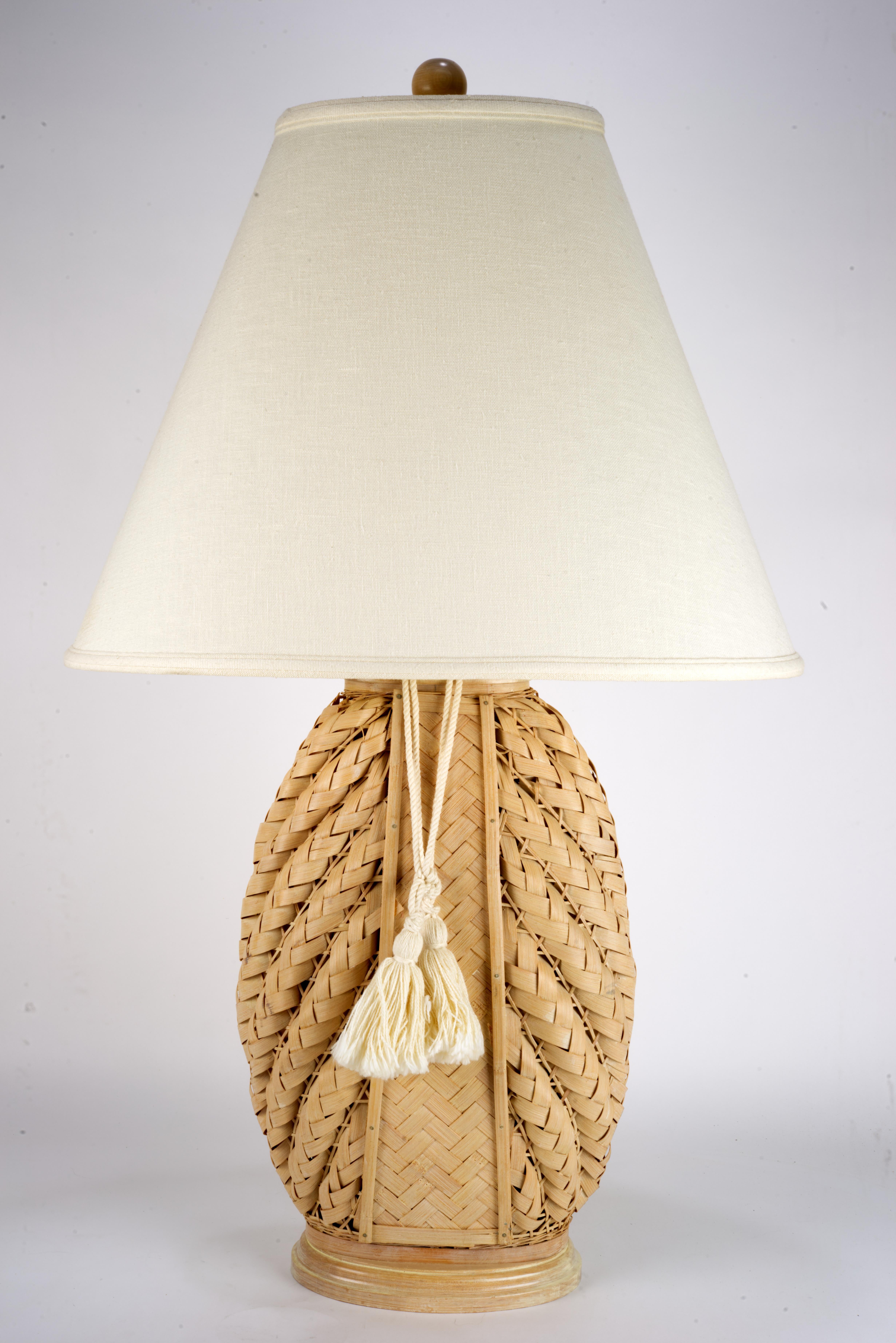  Seltene handgefertigte Rattanlampe mit leichtem Holzsockel, mit originalem Lampenschirm, Endstück und dekorativer Quaste. Ein komplexes, architektonisches Geflecht an den Seiten der Leuchte wird durch einen einfachen Parkettstreifen in der Mitte