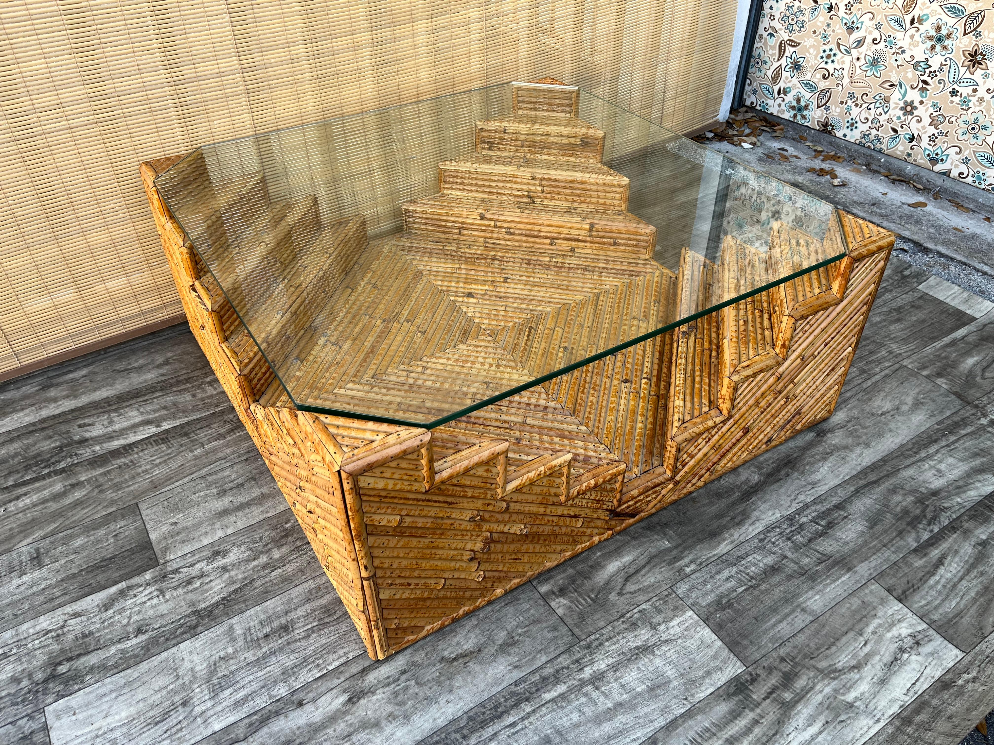 Sculptural Coastal Style Split Bamboo Coffee Table. Circa1980s
Features a monumental geometric design created by split bamboo nailed to the wooden frame, and a glass top with chamfered corners that seats on top of the table's corners.
In good