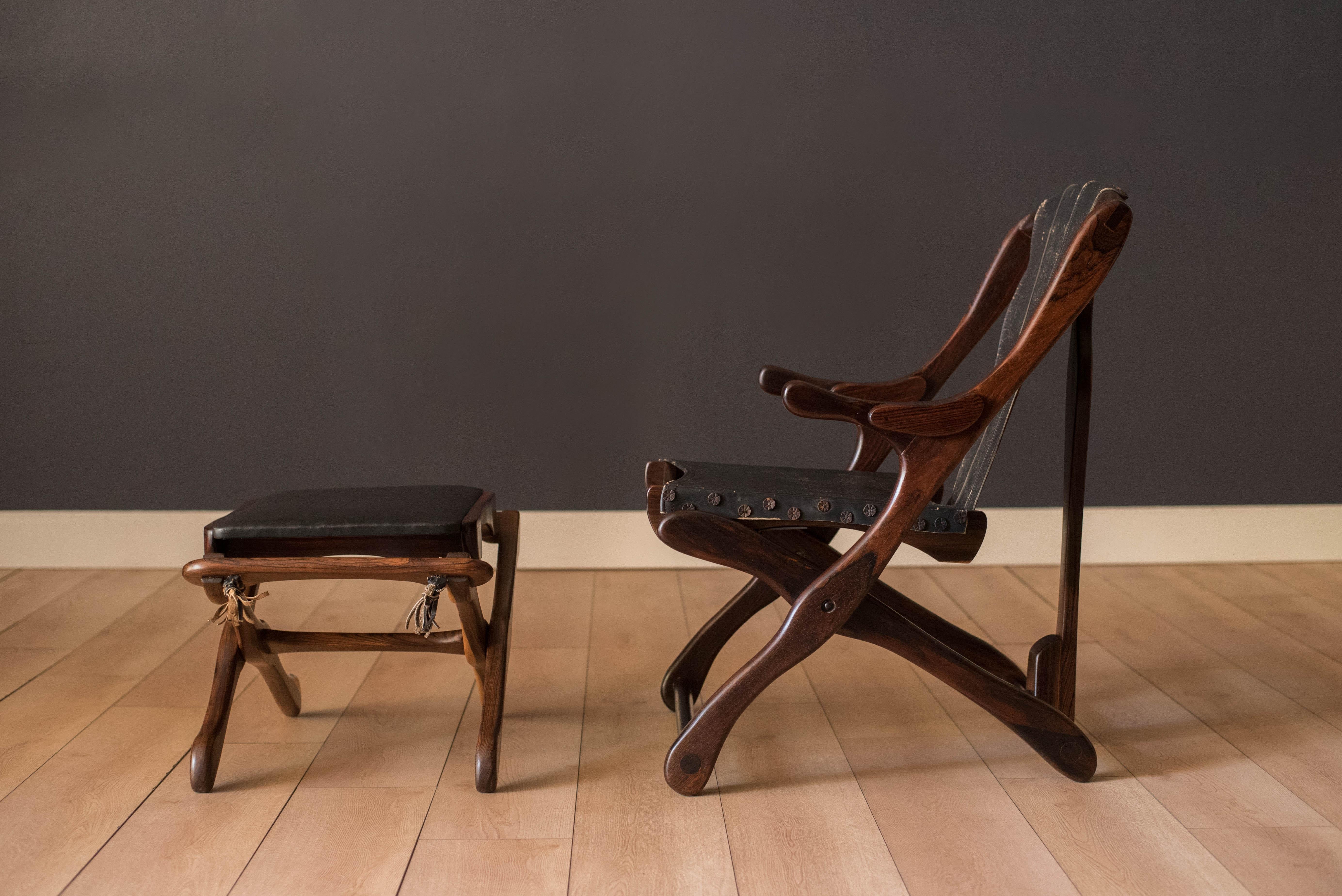 Mid-Century Modern leather sling lounge chair and ottoman designed by Don Shoemaker in cocobolo rosewood manufactured by Senal S.A., Mexico. This sculptural set features flowing rosewood grains and contrasting wood joinery. Equipped with folding