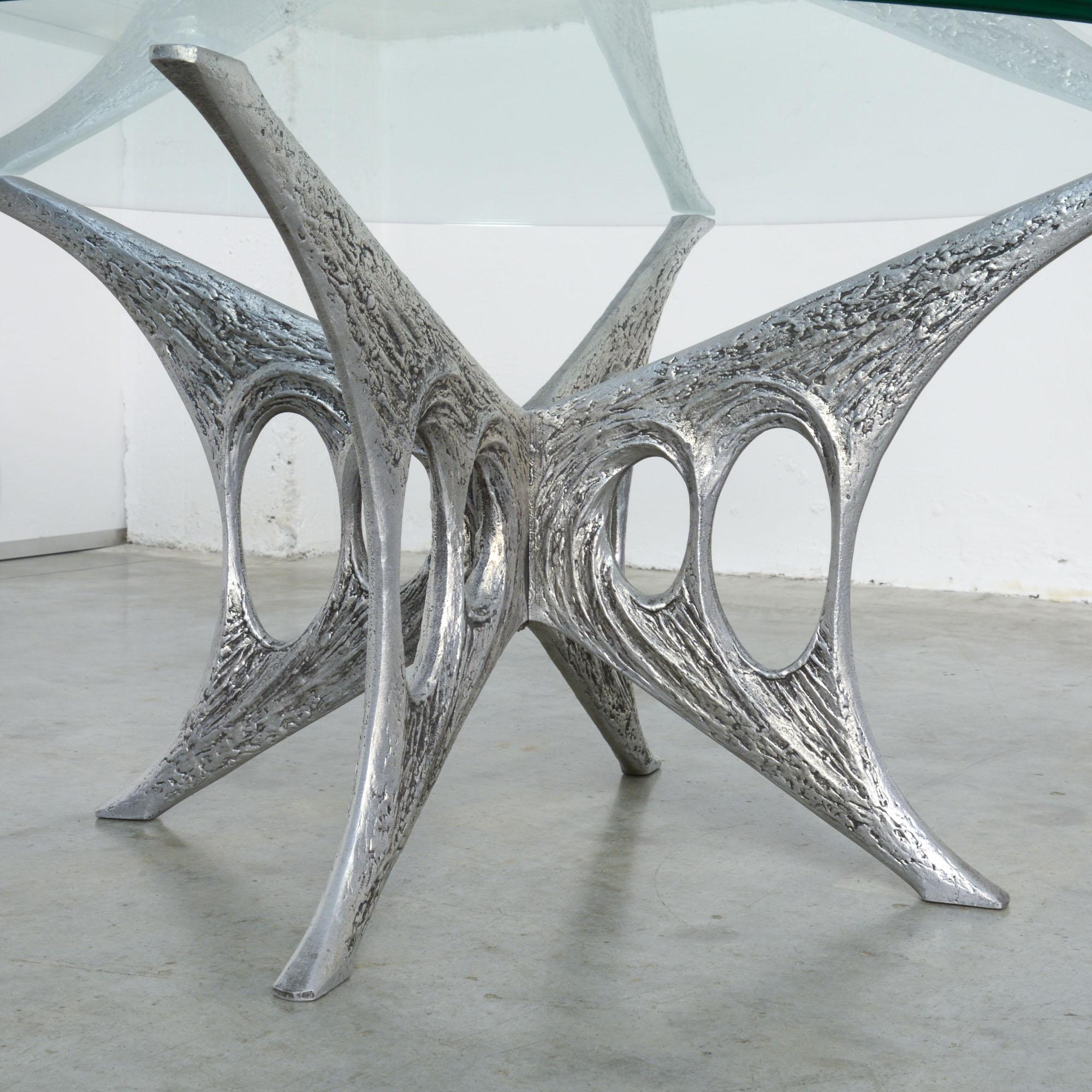 This aluminum coffee table is a nice example of the Brutalist work of the Belgian artist Willy Ceysens.
It is a unique piece, number 17.
The base is handmade of 2 pieces of cast aluminum. The table and thick glass tabletop are in very good