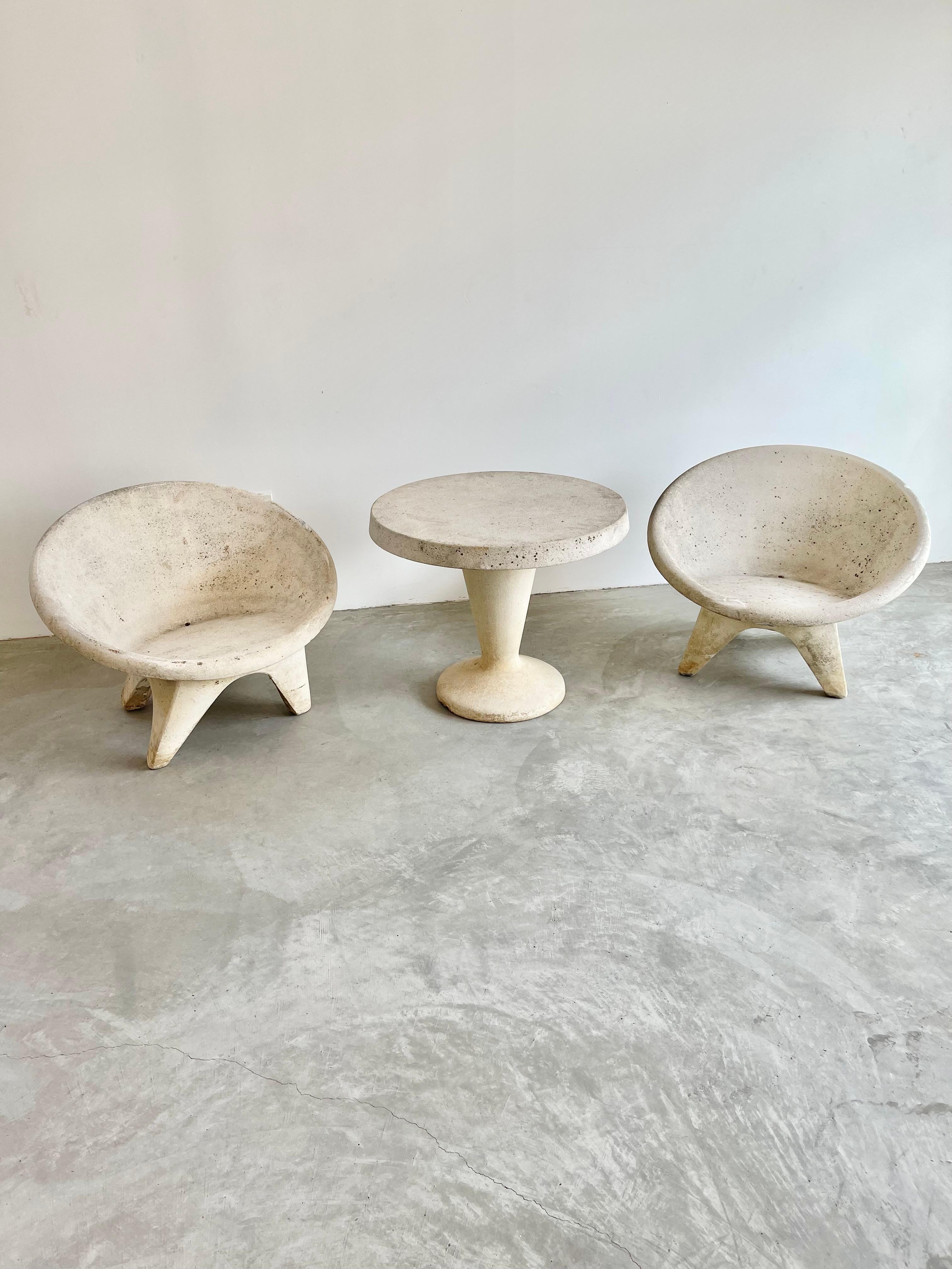 Stunning outdoor set consisting of two chairs with a matching table, all made of solid concrete. Round saucer seat with angular lets. Incredible modern design with very light patina. Factory drilled hole in each chair for water to drain. Great