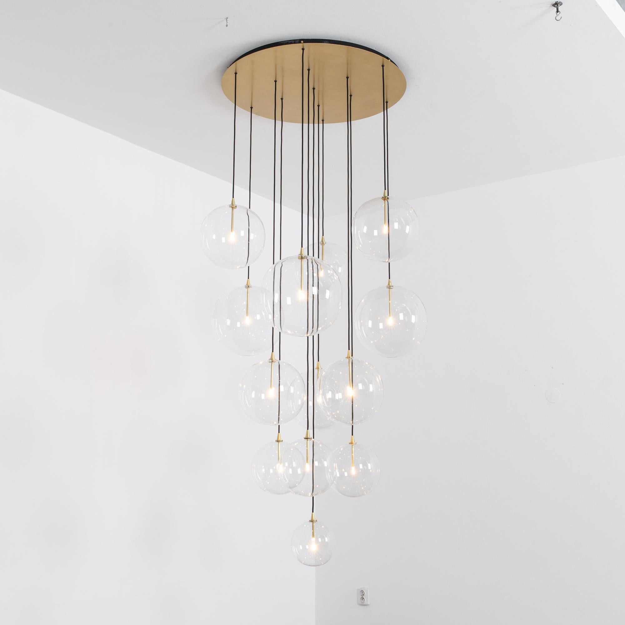 Cluster 13 Mix Brass Chandelier by Schwung
Dimensions: D 112.5 x W 104 x H 320 cm  
Materials: Natural brass, hand blown glass globes

Glass globes diameter 35 / 30 / 25 / 20 / 15 cm
Max wattage 1.6W
Bulb base G4, 12V AC
Lumens 1000lm
Color