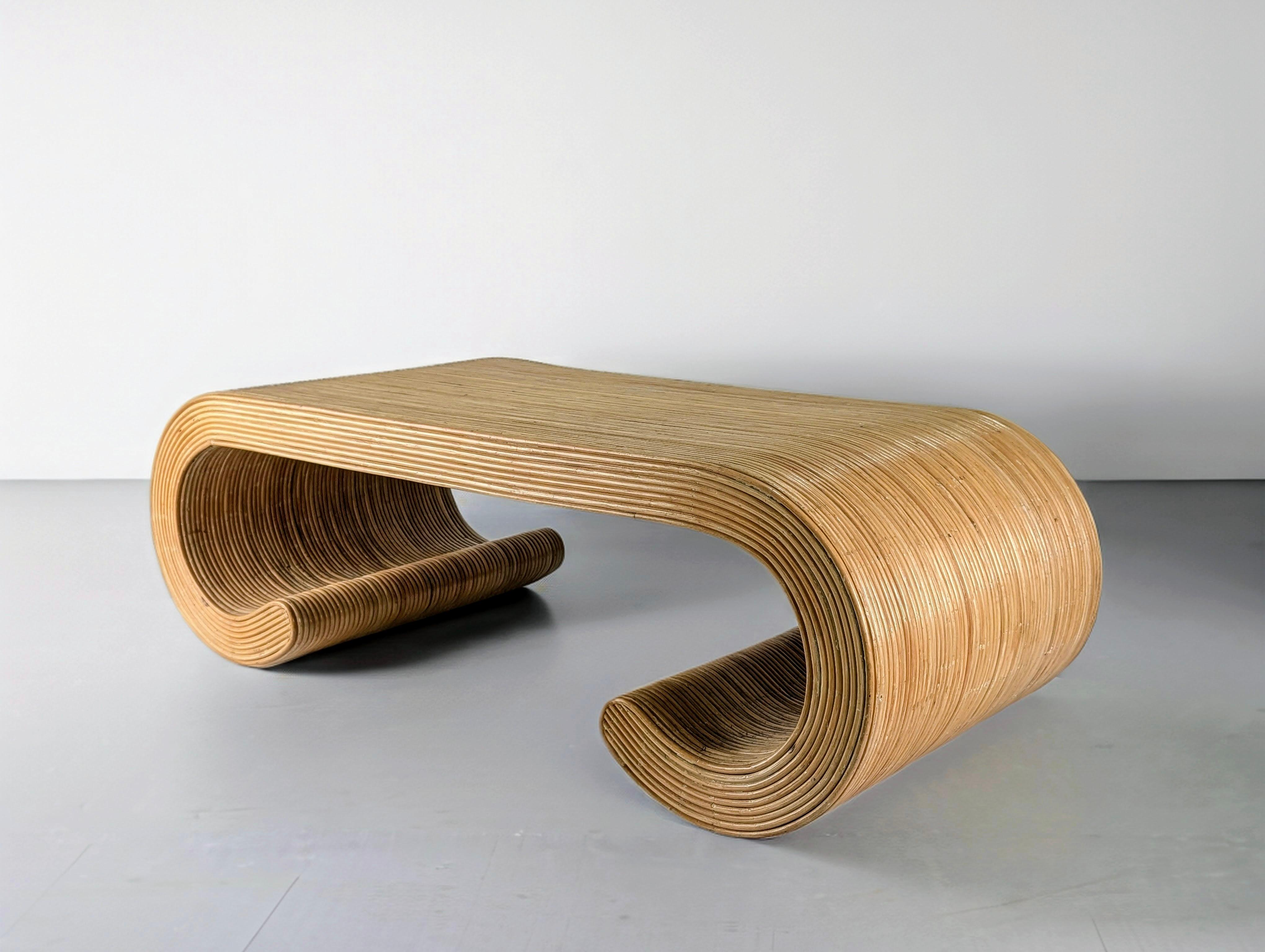 Sofisticada mesa de centro vintage de los años 70, elaborada en ratán natural con un escultural diseño curvo que evoca elegantes formas orgánicas. La estructura está hecha de tiras de ratán finamente estratificadas y expertamente dobladas, creando