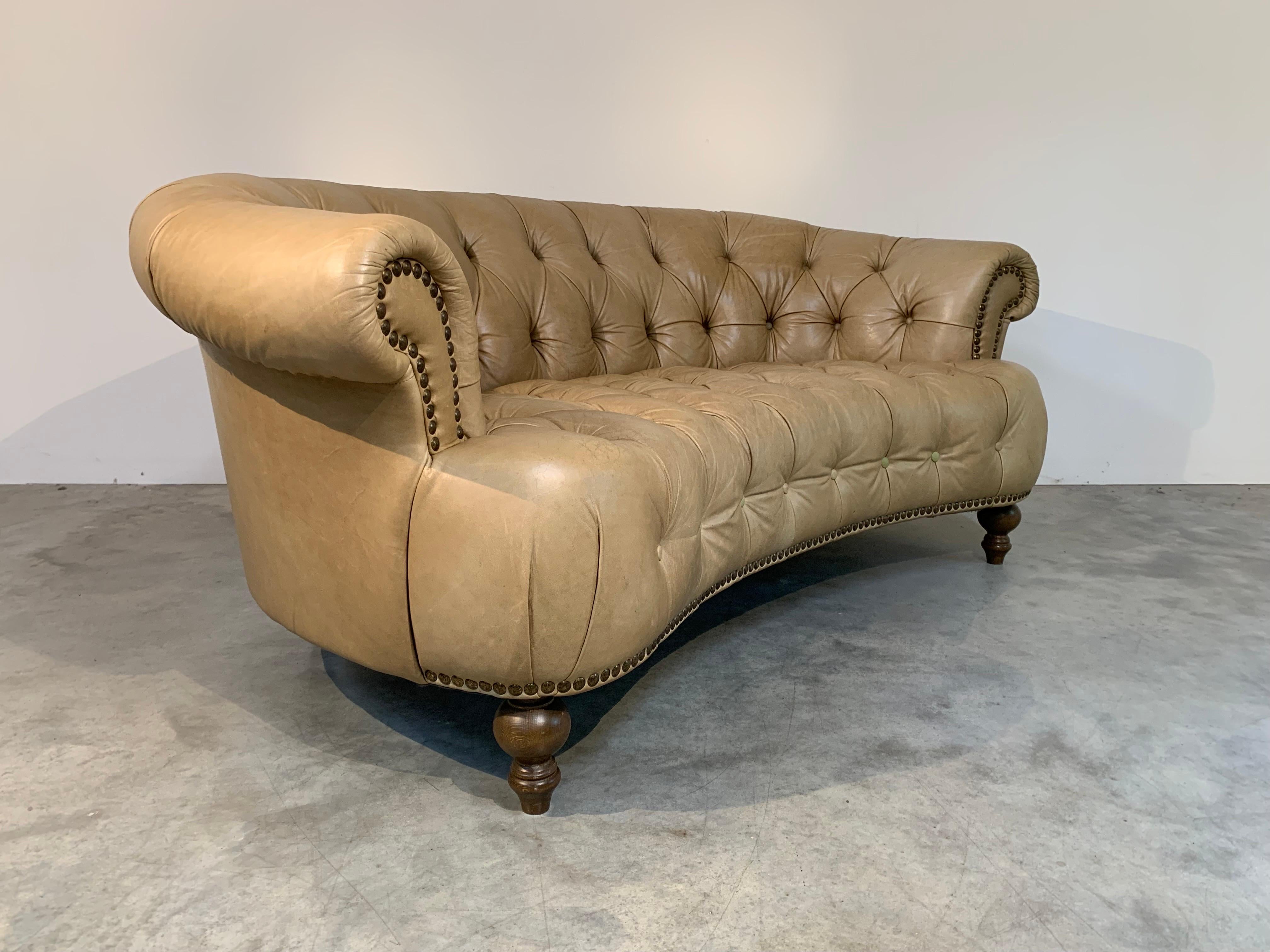 Iconic Chesterfield vintage sofa that was made in Italy and is hallmarked as such having the coveted curvature frame over turned walnut legs  in the design of a Chesterfield sofa, which are typically straight. The leather on this piece is soft and