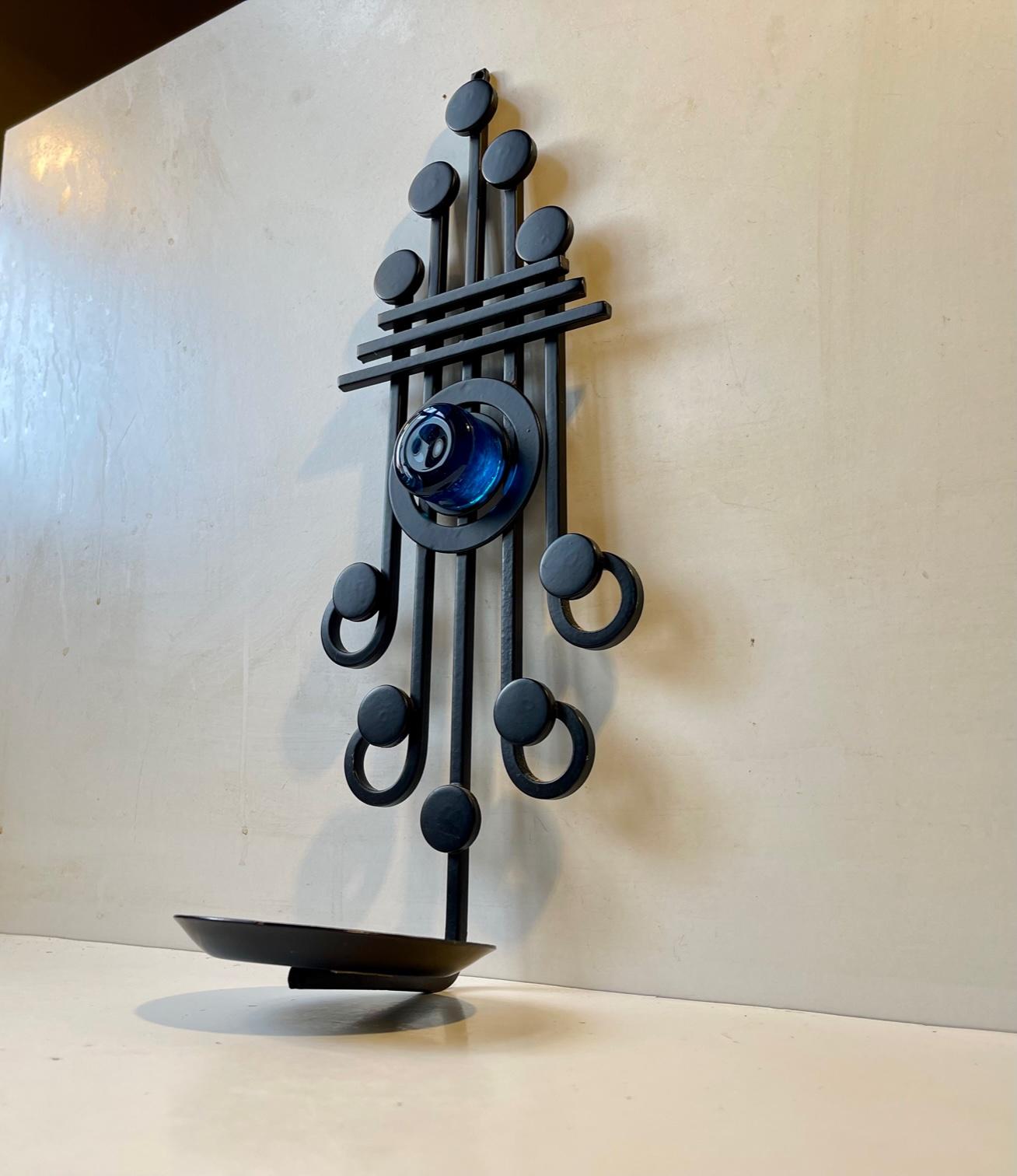 1970s Brutalist Wall sculpture made by Danish design company Dantoft kunstartikler (trans.: art objects). It is made from black lacquered and welded iron set in a graphic formation highlighted by thick blue glass mosaic. It can be installed with a