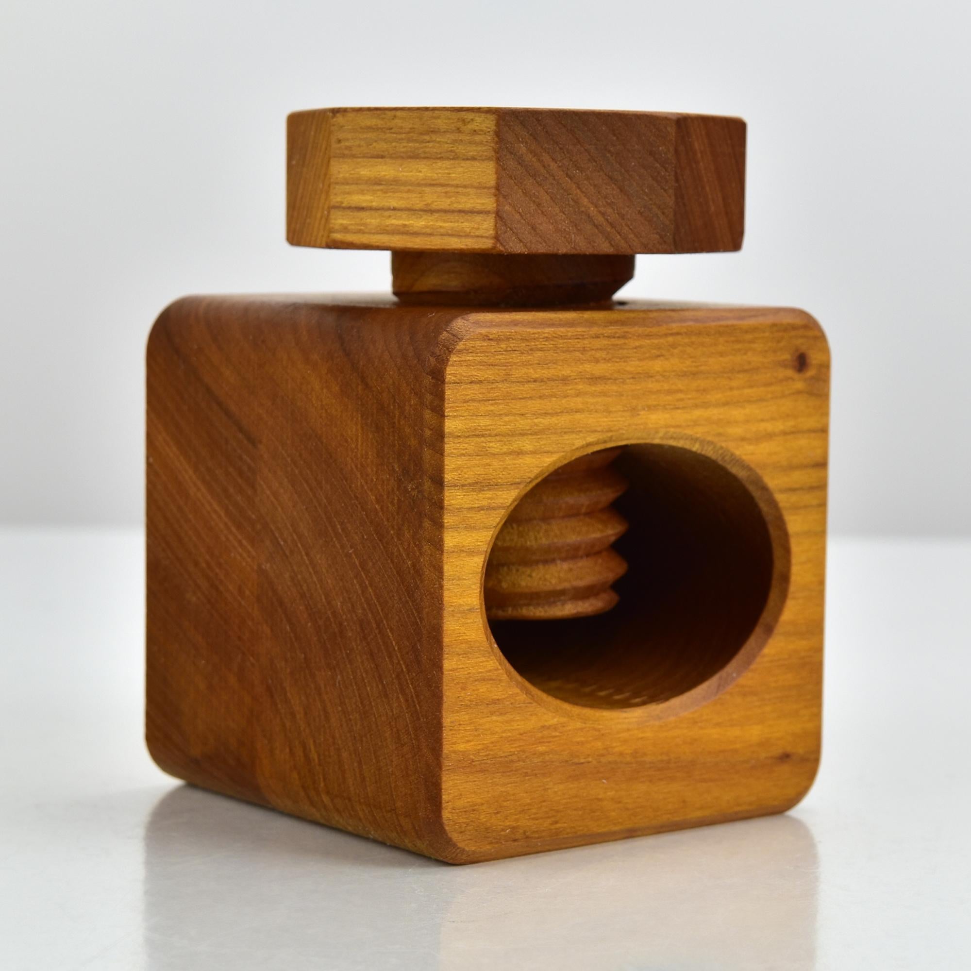 This vintage Danish Modern nutcracker is a beautifully crafted piece made of solid teak wood, designed in the functional yet sculptural style often associated with Jens Quistgaard. Its cube-shaped body with rounded edges features a deeply carved