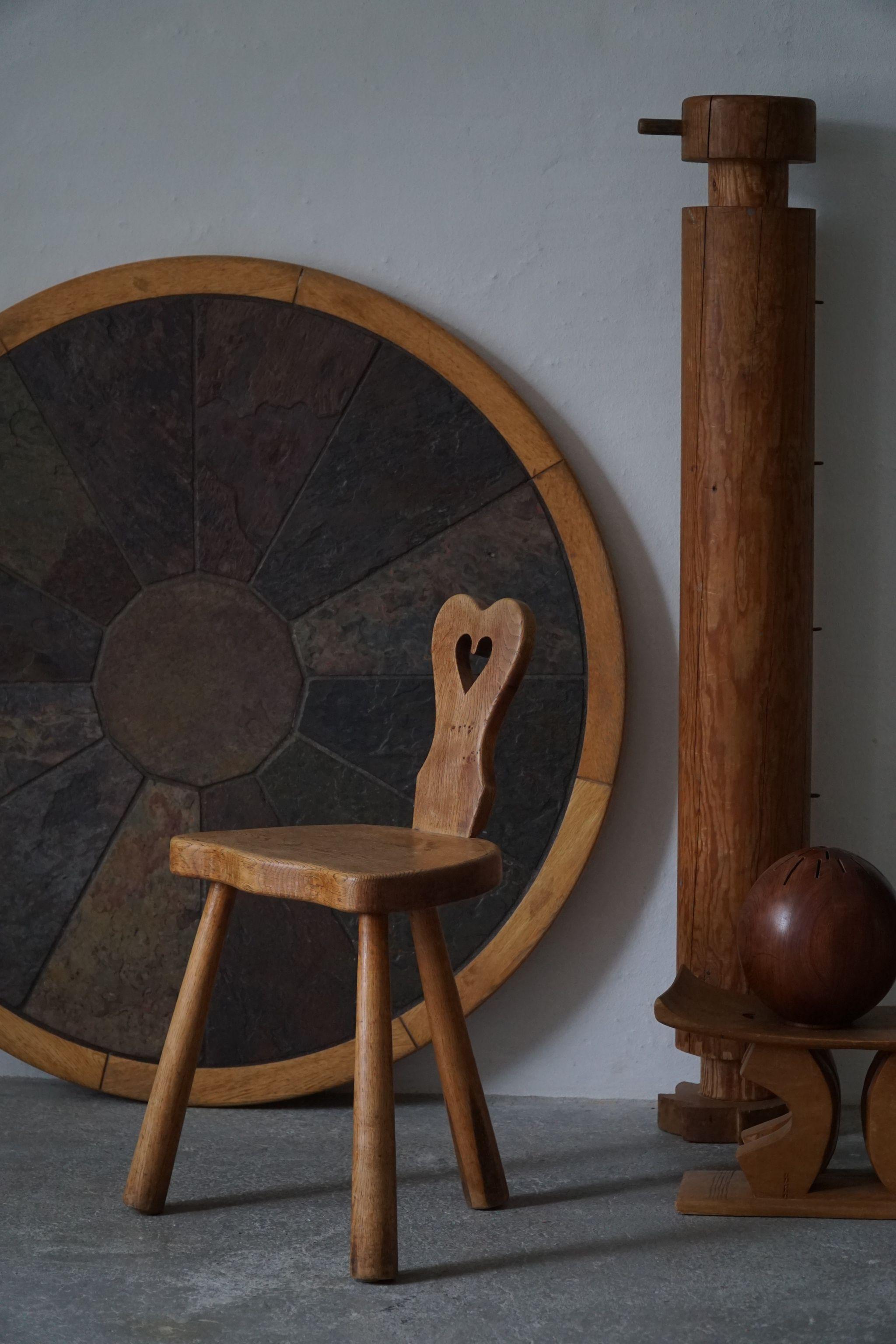 A sculptural vintage tripod heart chair in solid oak with club legs, made in Denmark, early 20th century.

A great decorative object for the modern interior. A warm patina that pair well with the minimalist scandinavian lifestyle. Scandinavian