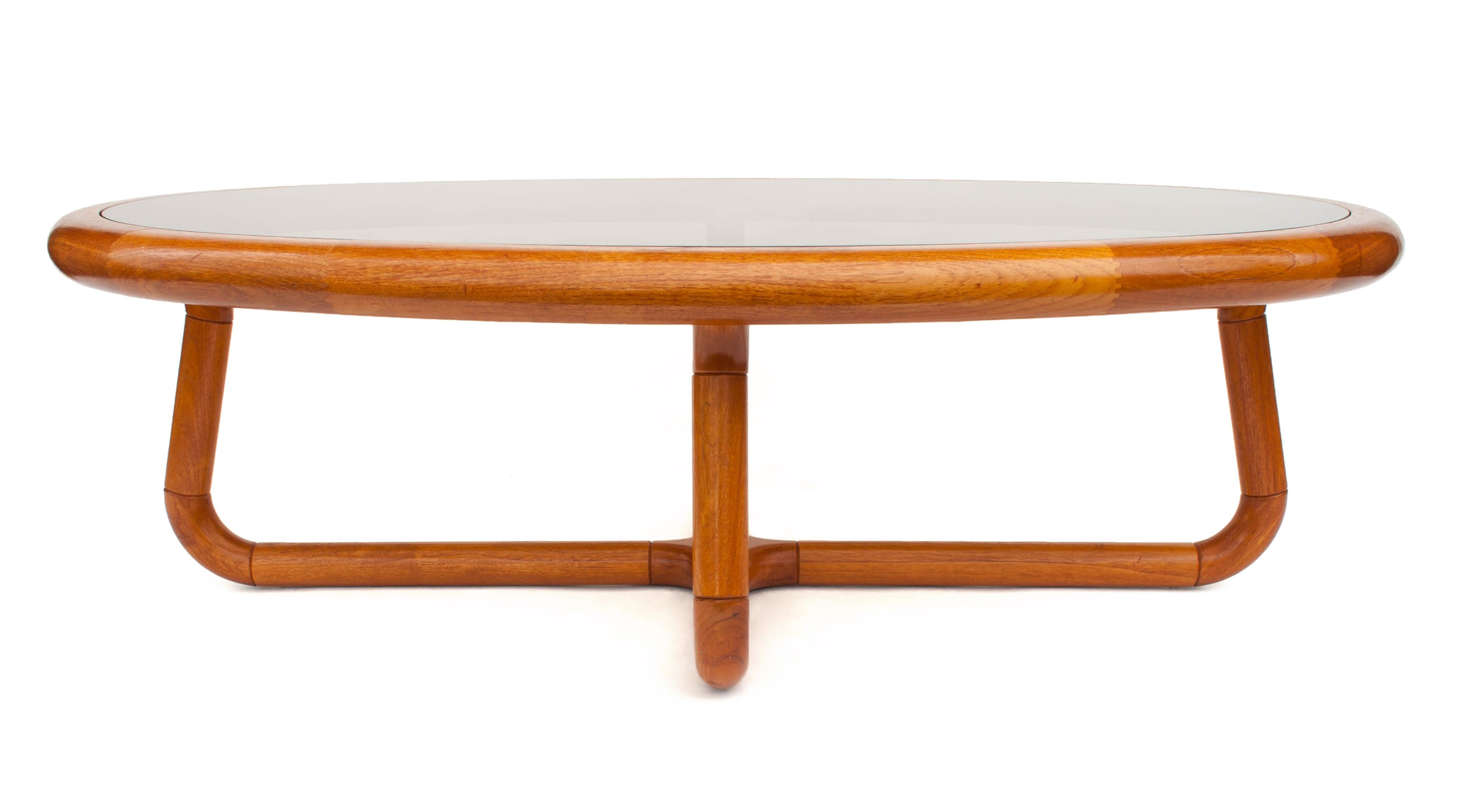Uncommon midcentury sculptural teak coffee table with smoked glass by Uldum Mobelfabrik. This elegant Danish table is oval in shape and made from curved teak sections. Original label on bottom.
     