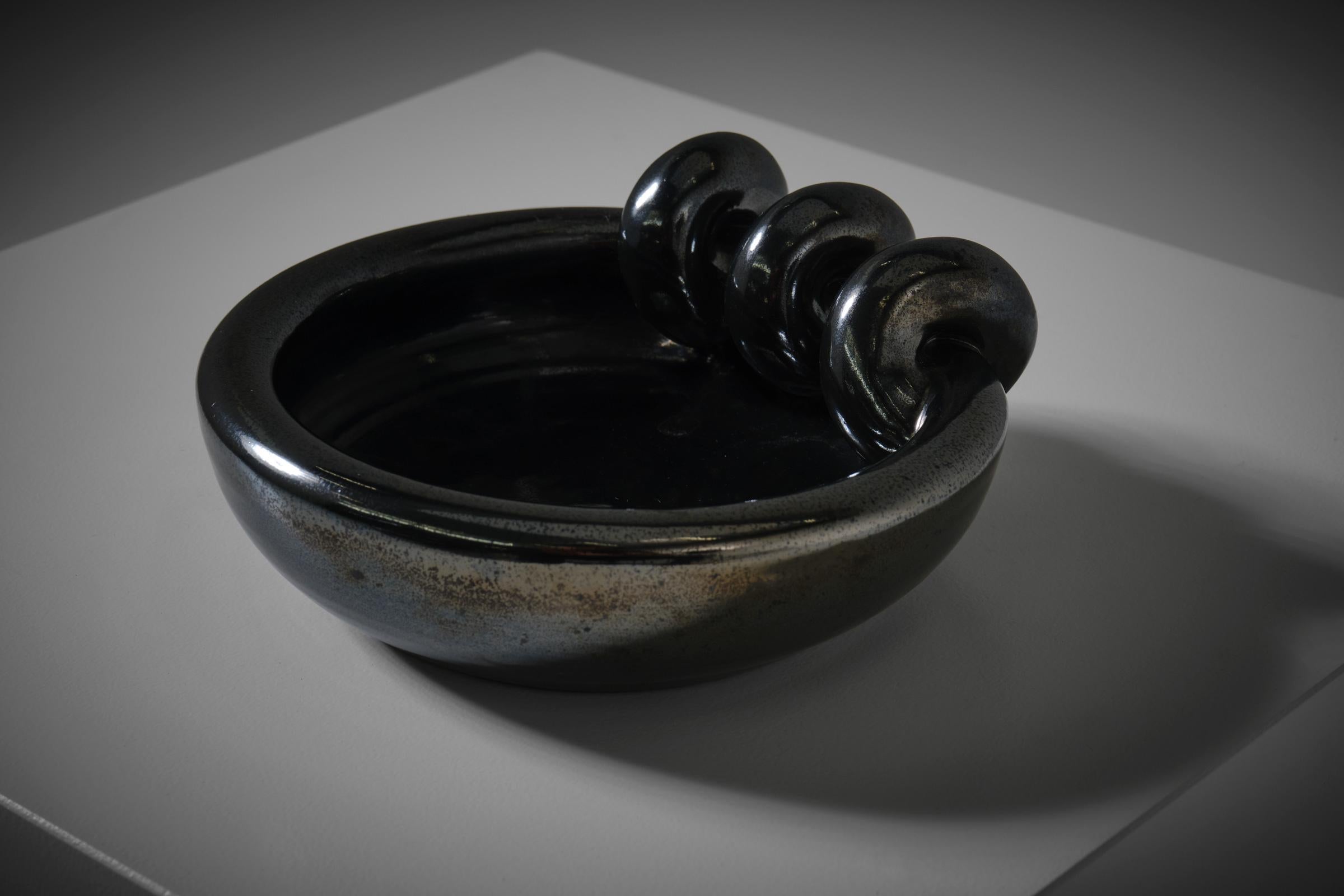 Sculptural dark metallic glazed ceramic vide poche, France 1960s. Beautiful well crafted thick bowl; nice fat lobed shapes in a wonderful black - graphite glaze. The surface shows a subtle structure and a nice metallic shine. Signed at the bottom: