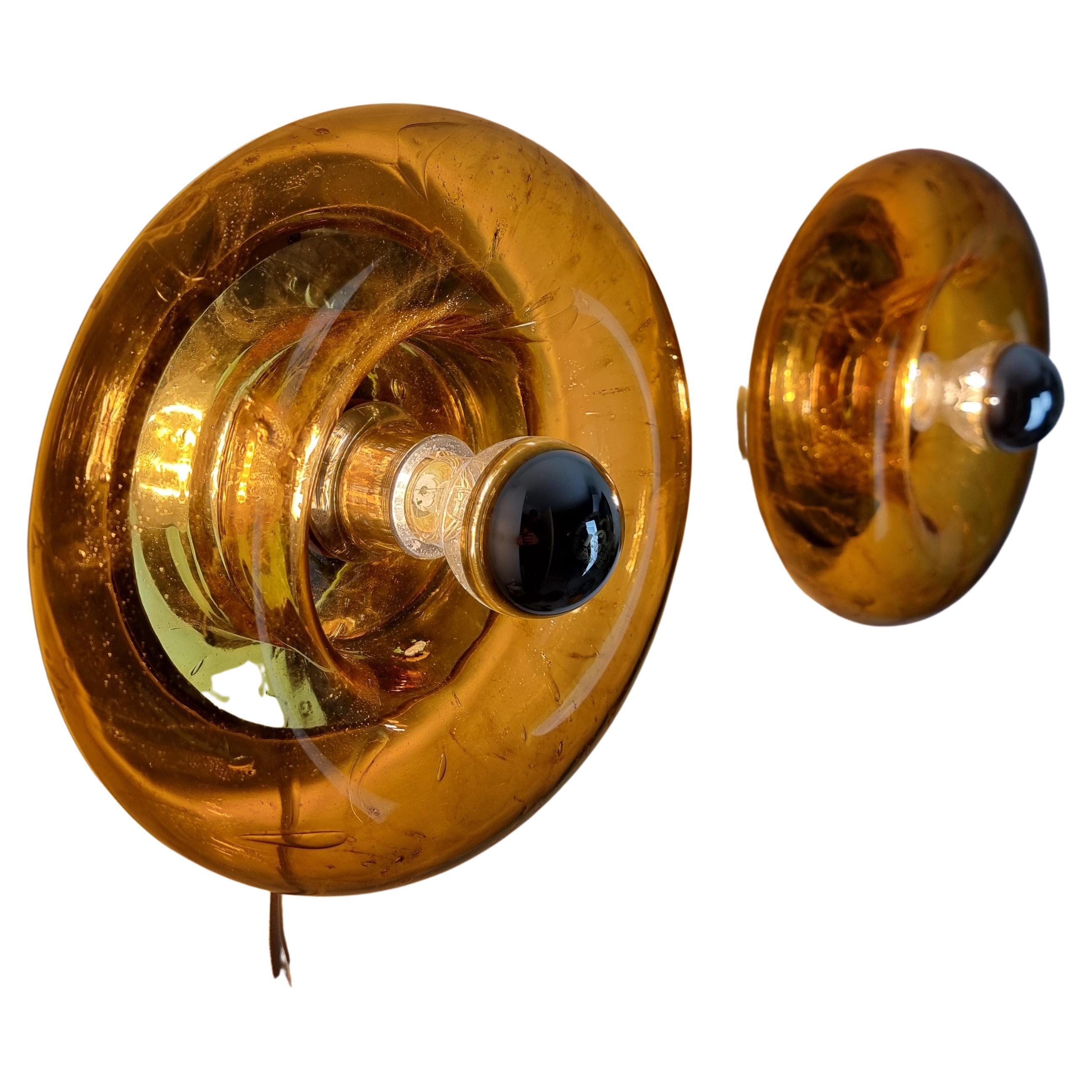 This pair of Murano glass flush mounts or wall sconces by Doria are a beautiful and colorful addition to any space. The Murano glass is crafted in the shape of a donut, creating a unique and eye-catching design.

The glass is in excellent