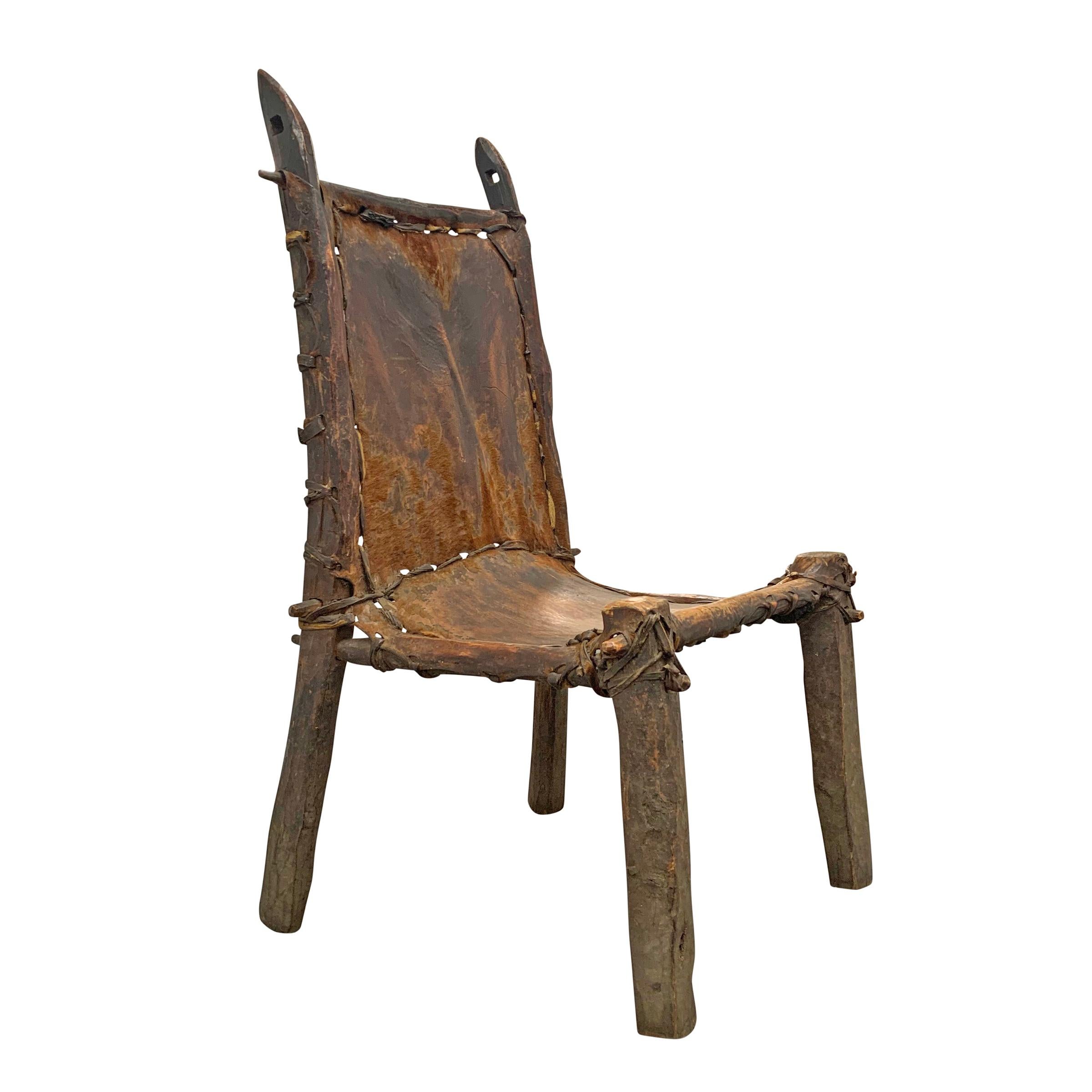 A wonderfully sculptural early 20th century Ethiopian side chair with a hide seat and back stitched with hide strips, and stretched over a primitive wood frame. Chair is functional, but it is more sculptural object than comfortable perch.