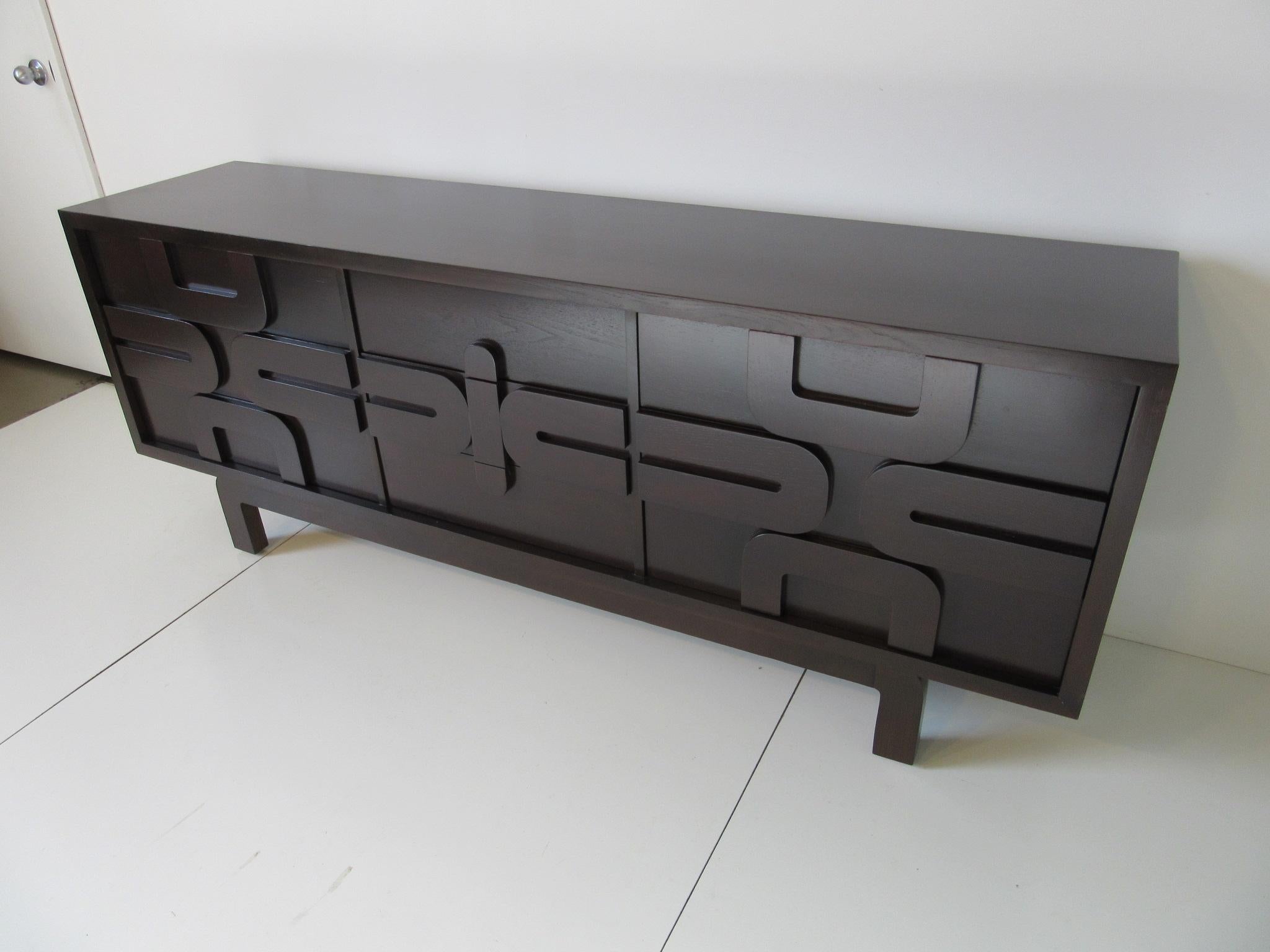 A ebony toned nine-drawer dresser chest with sculptural designed details to the front and curved legs that blend into the total look. This piece has a nice simple clean sophisticated feel with the it's rich finish and ample storage, manufactured by