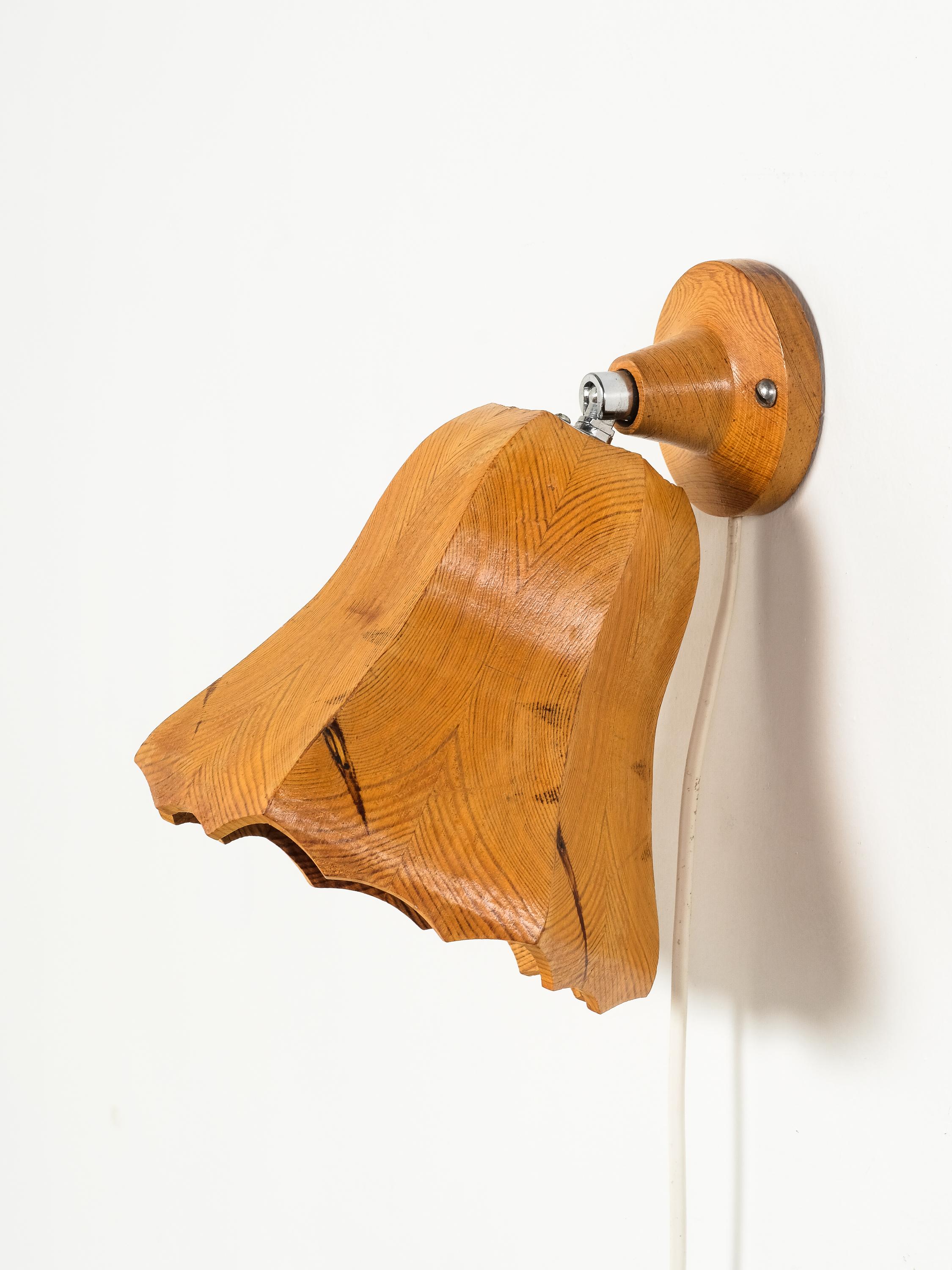 A sculptural Finnish wall lamp from the 1970s, expertly hand-carved from solid pine. The organic, flower-like shade features a beautifully scalloped edge and rich natural grain that celebrates the material’s character, including visible knots and