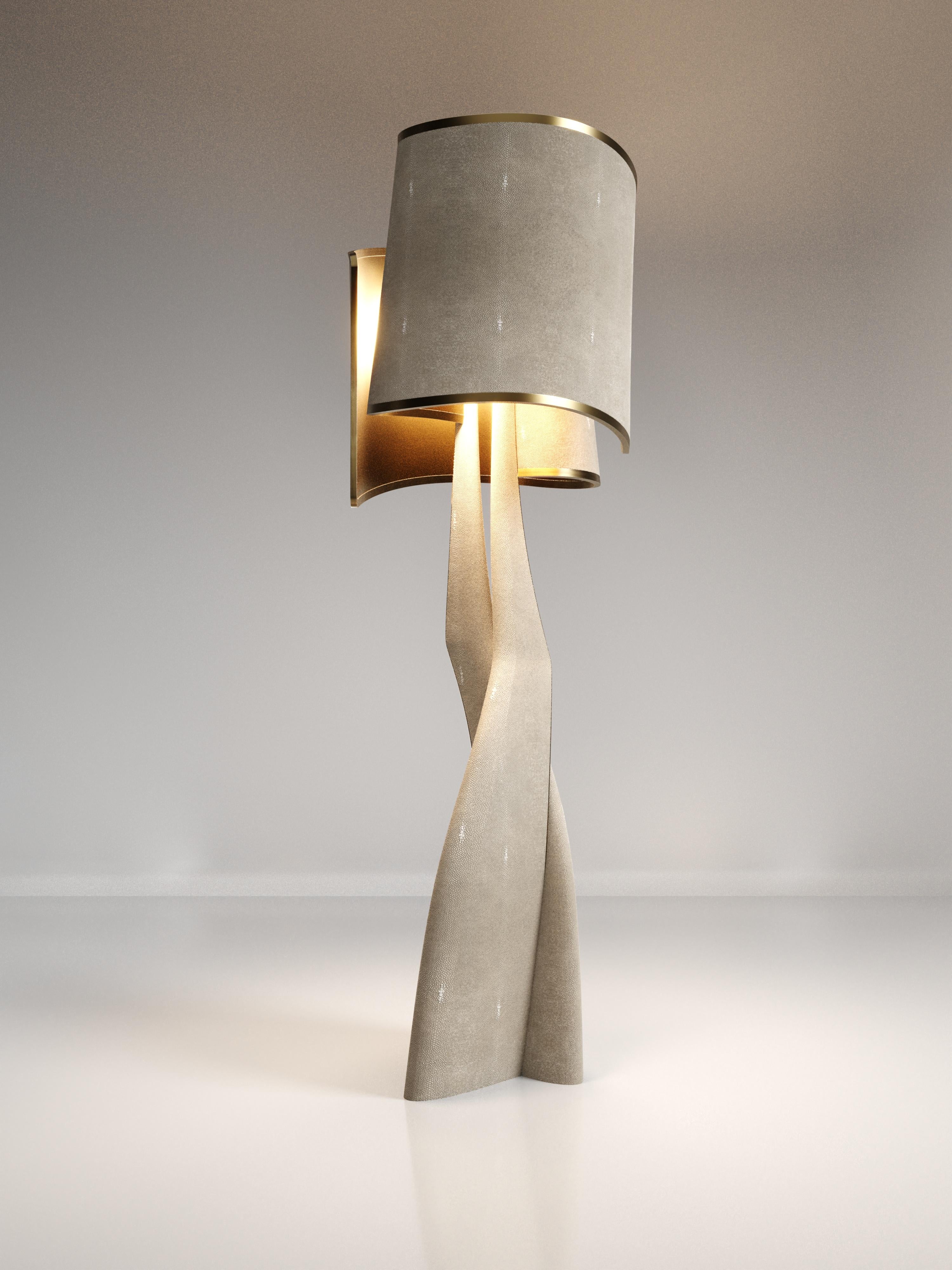 The Chital III Floor Lamp by Kifu Paris is a sleek and sculptural piece, inlaid in a mixture of bronze-patina brass and cream shagreen. The chiseled legs, which are an iconic shape within the KIFU PARIS universe, morph into the solid shades that