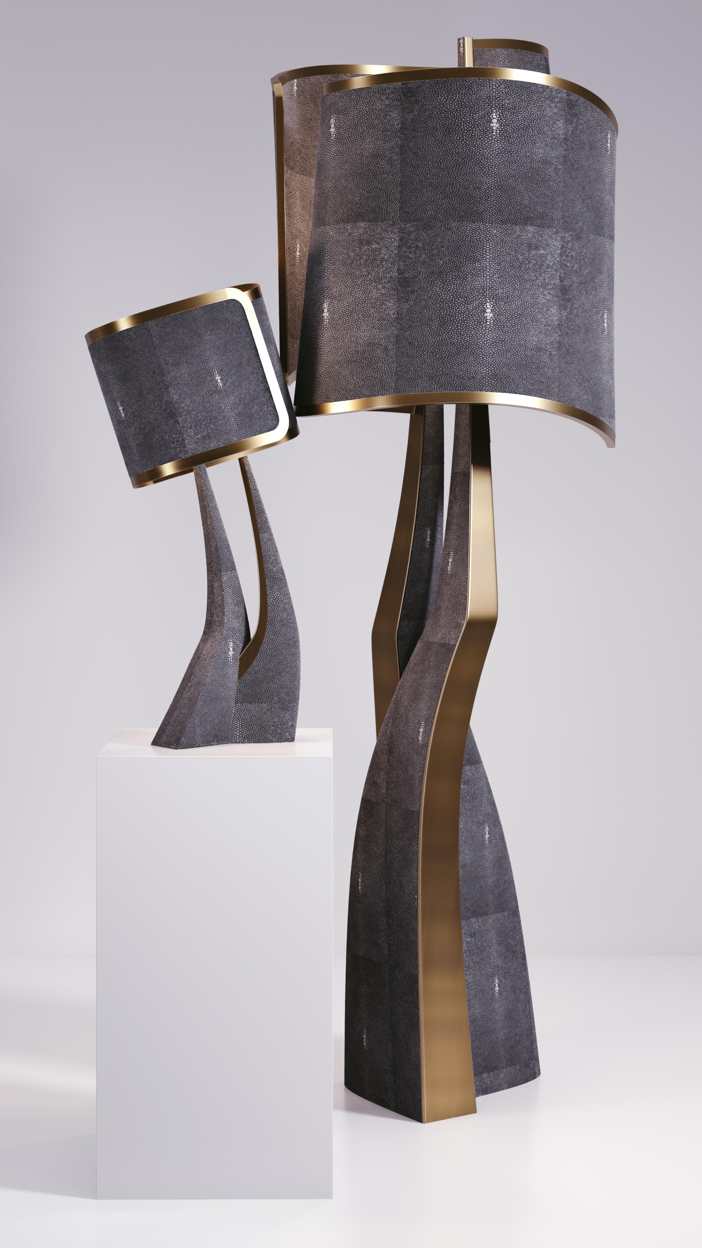 The Chital III Floor Lamp by Kifu Paris is a sleek and sculptural piece, inlaid in a mixture of bronze-patina brass and col black shagreen. The chiseled legs, which are an iconic shape within the KIFU PARIS universe, morph into the solid shades that