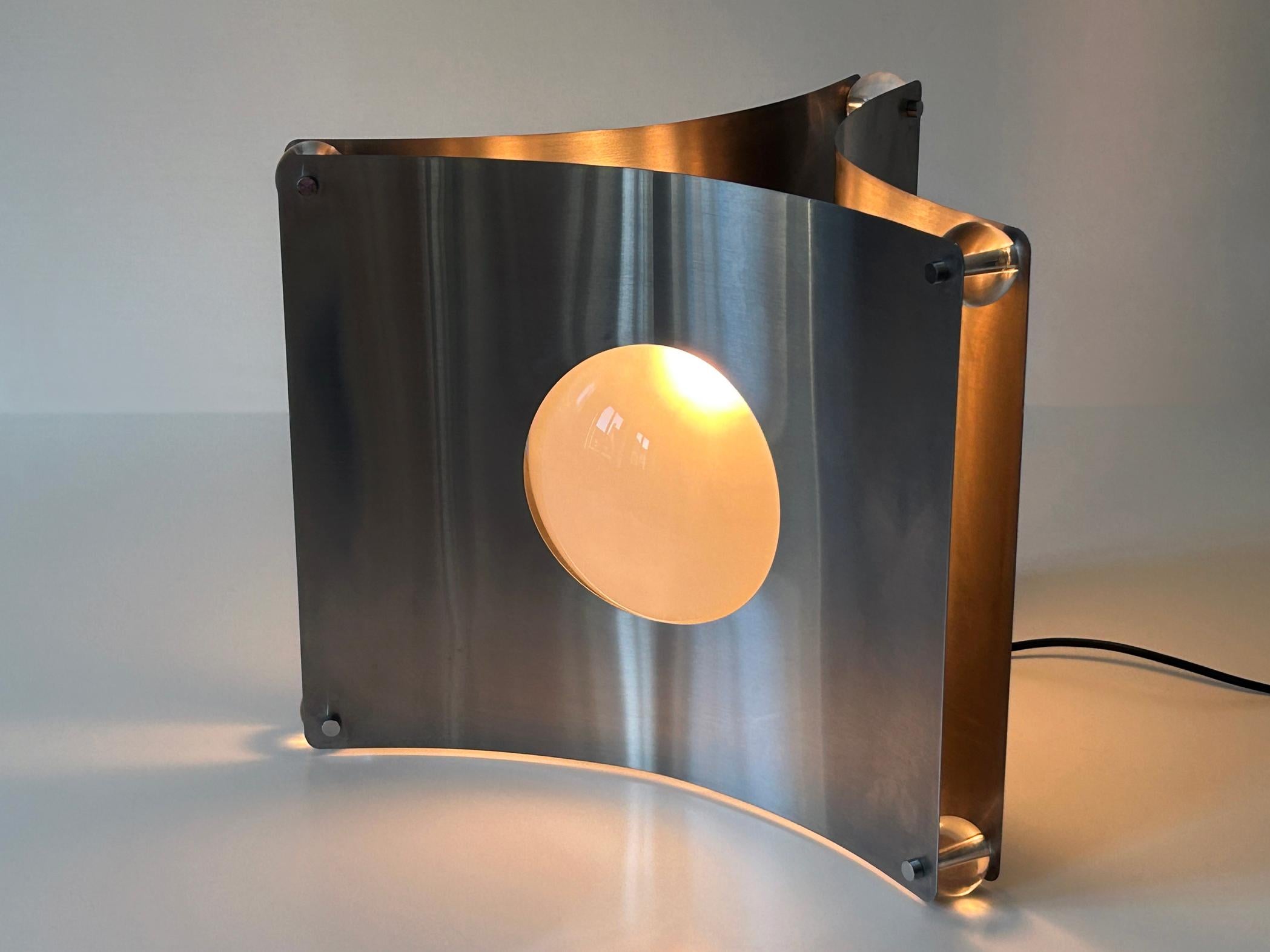 Lampada da terra o da tavolo scultorea in stile Mid-Century Modern. Disegnata da Luigi Massoni per Guzzini, Italia, anni '60.

Realizzata in acciaio inossidabile, vetro semi-opaco e lucite, la lampada è dotata di 1 portalampada a vite E27 / E26 di