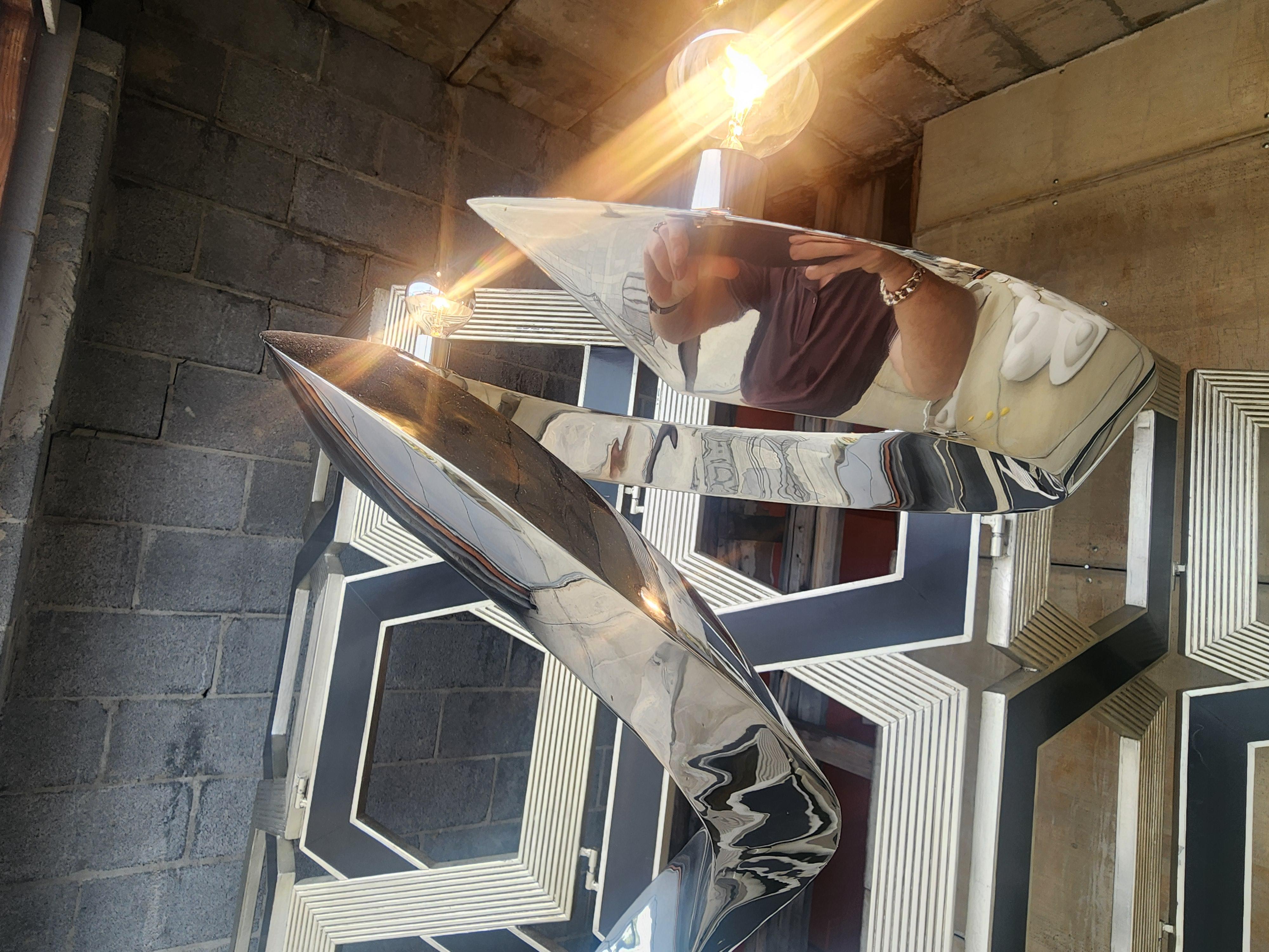 Lampadaire en acier inoxydable forgé à la main par l'artiste Curtis Norton, présentant une barre triangulaire qui s'incurve et se termine par un anneau à trois douilles.   Une œuvre d'art qui est aussi une source de lumière,   Cette lampe est sortie