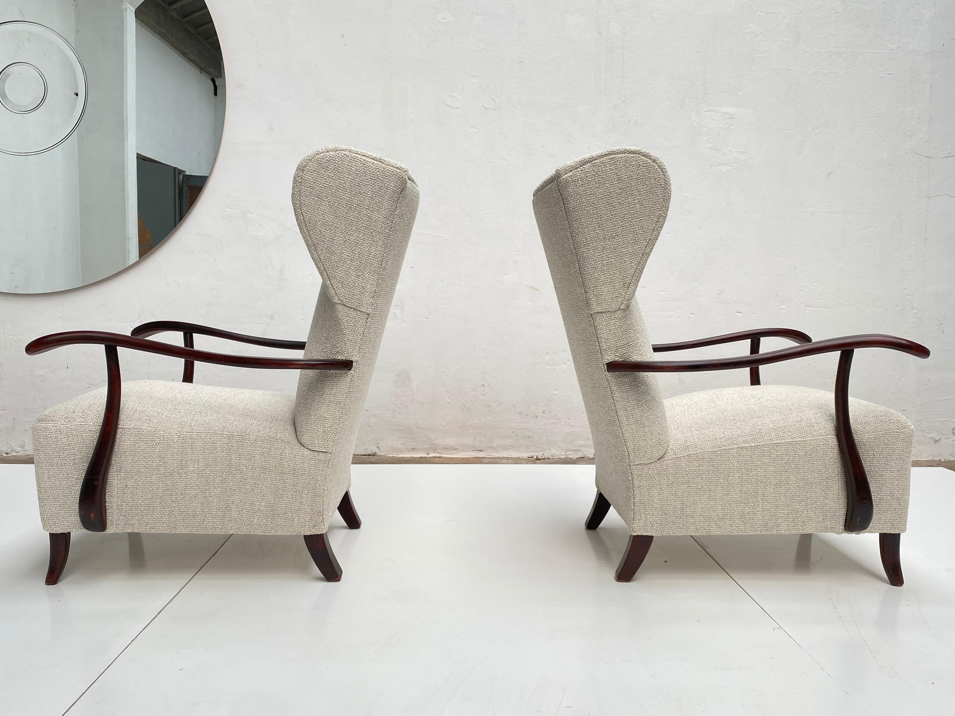 Lovely pair of 1940s sculptural form, wing back chairs attributed to the italian architect and designer Paolo Buffa who learned his trade in Gio Ponti's studio in the late 1920s. The chairs feature a beautiful flowing hardwood armrest design which