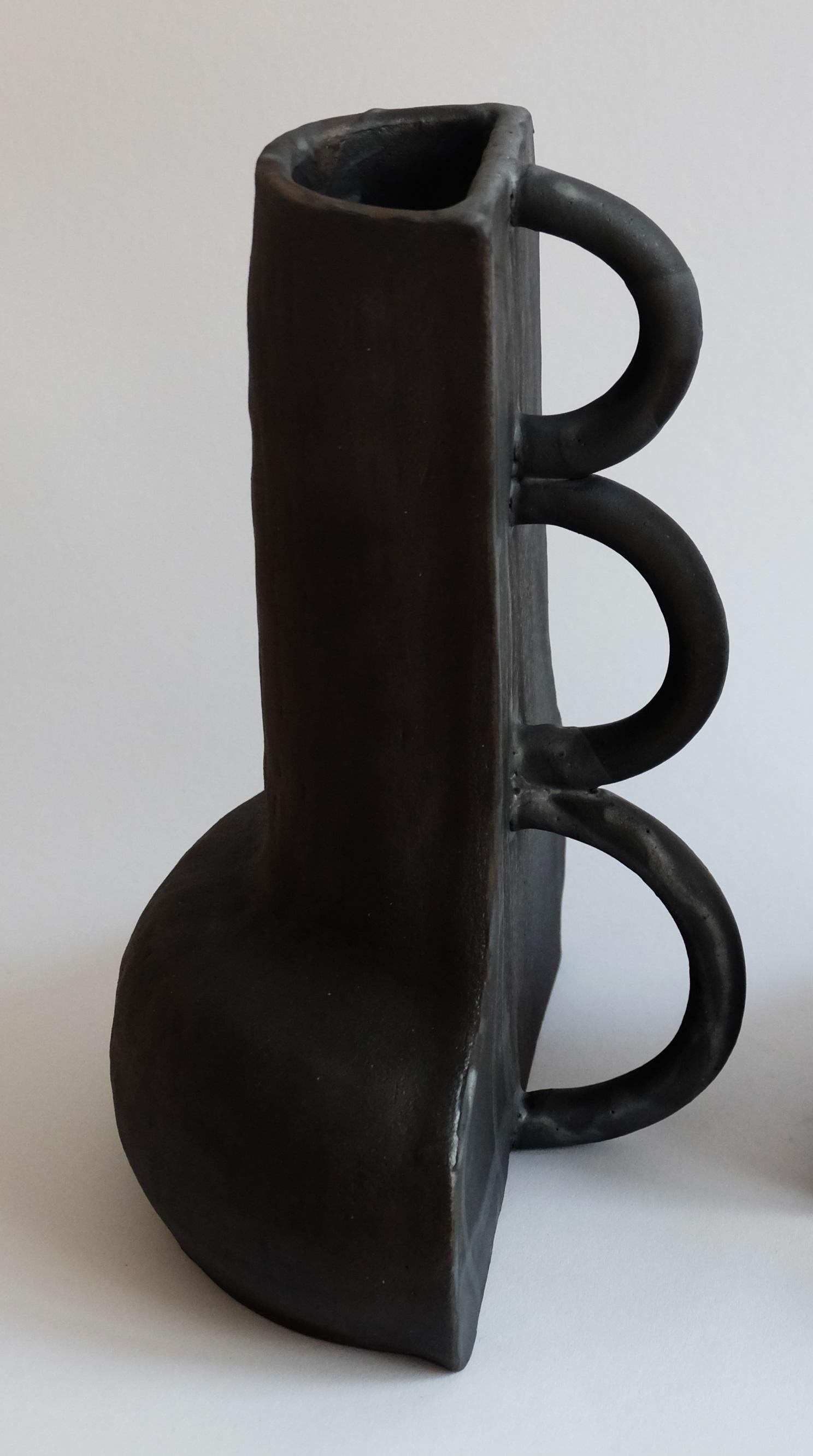 Skulpturale Fragmentvase von Ia Kutateladze
Abmessungen: B 20 x H 30 cm
MATERIALIEN: Roher schwarzer Ton

Die Vase Fragment 01 ist ein skulpturales, funktionales Objekt, das aus schwarzem Ton handgefertigt wurde. Die kontrastierenden Seiten -