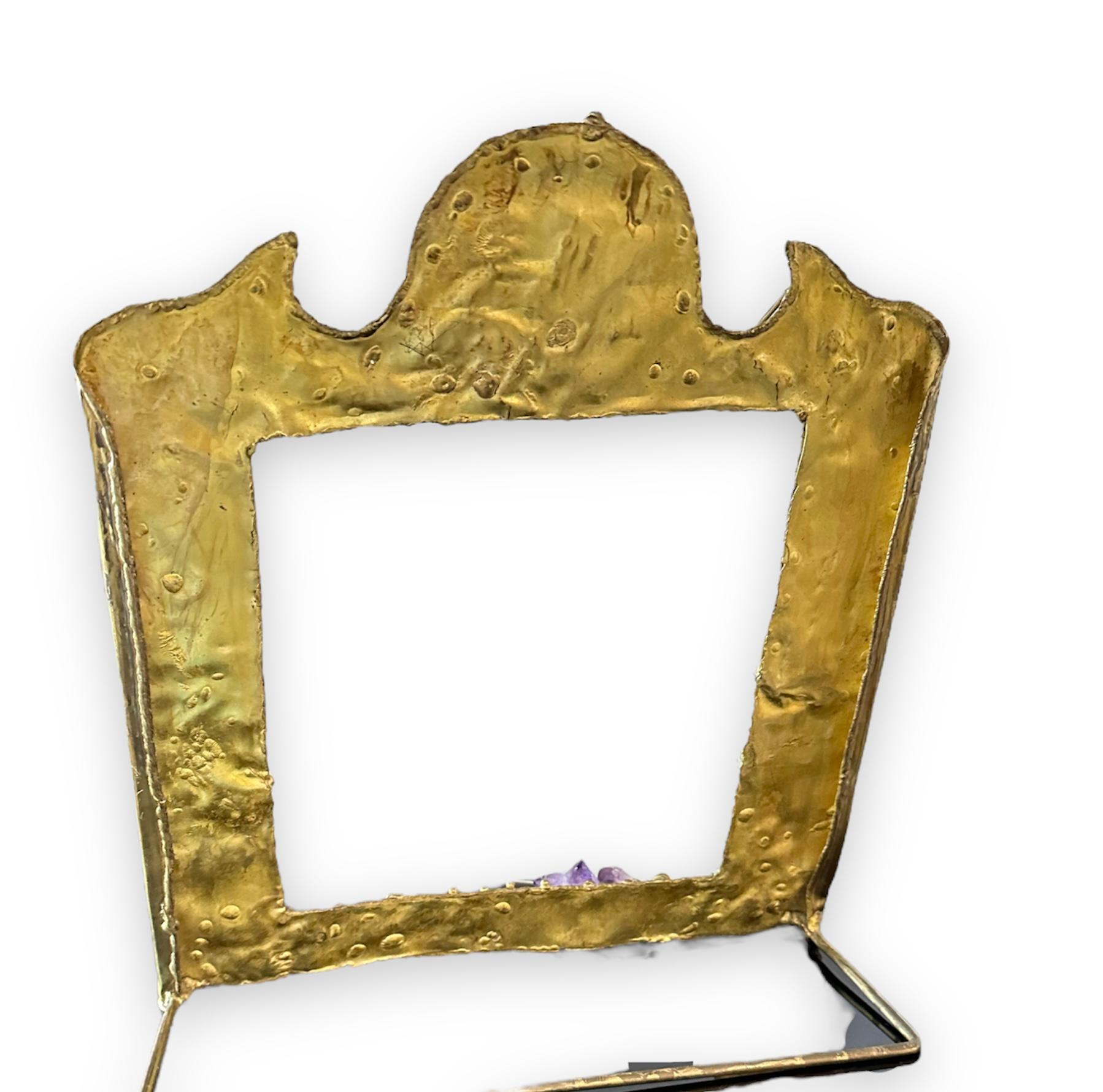One of a kind hand-wrought textural and dimensional picture frame is a mixed media of brass with inlays of copper hints.
The jeweled like frame/mirror has dimensional juttings of raw amethyst, rose quartz and agate. It is sculptural and