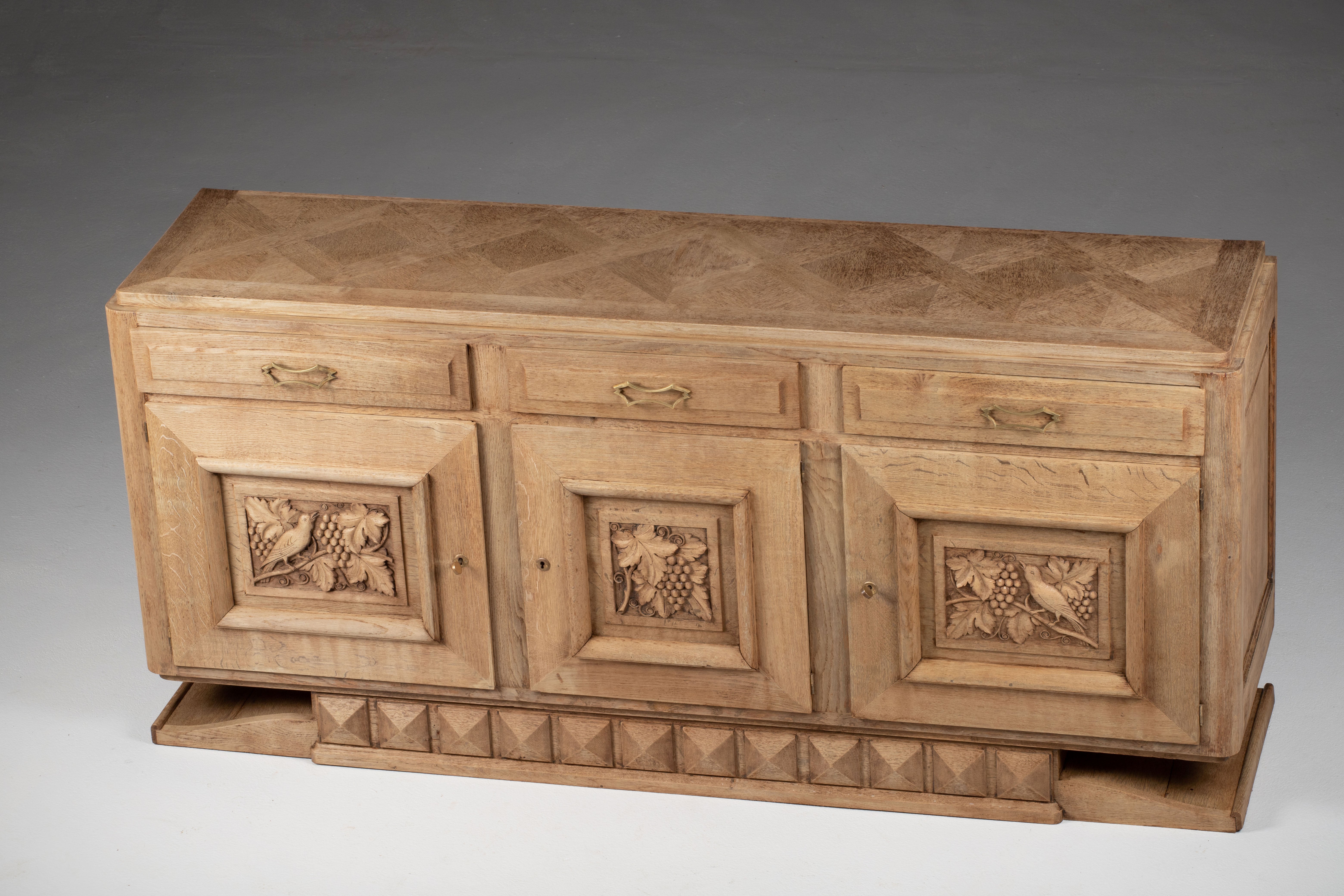 Very elegant credenza in solid oak, France, 1940s.
Art Deco Brutalist sideboard. 
The credenza consists of Two storage facilities covered with handcarved vines designed doors and a column of drawers.
The refined wooden structures on the doors create