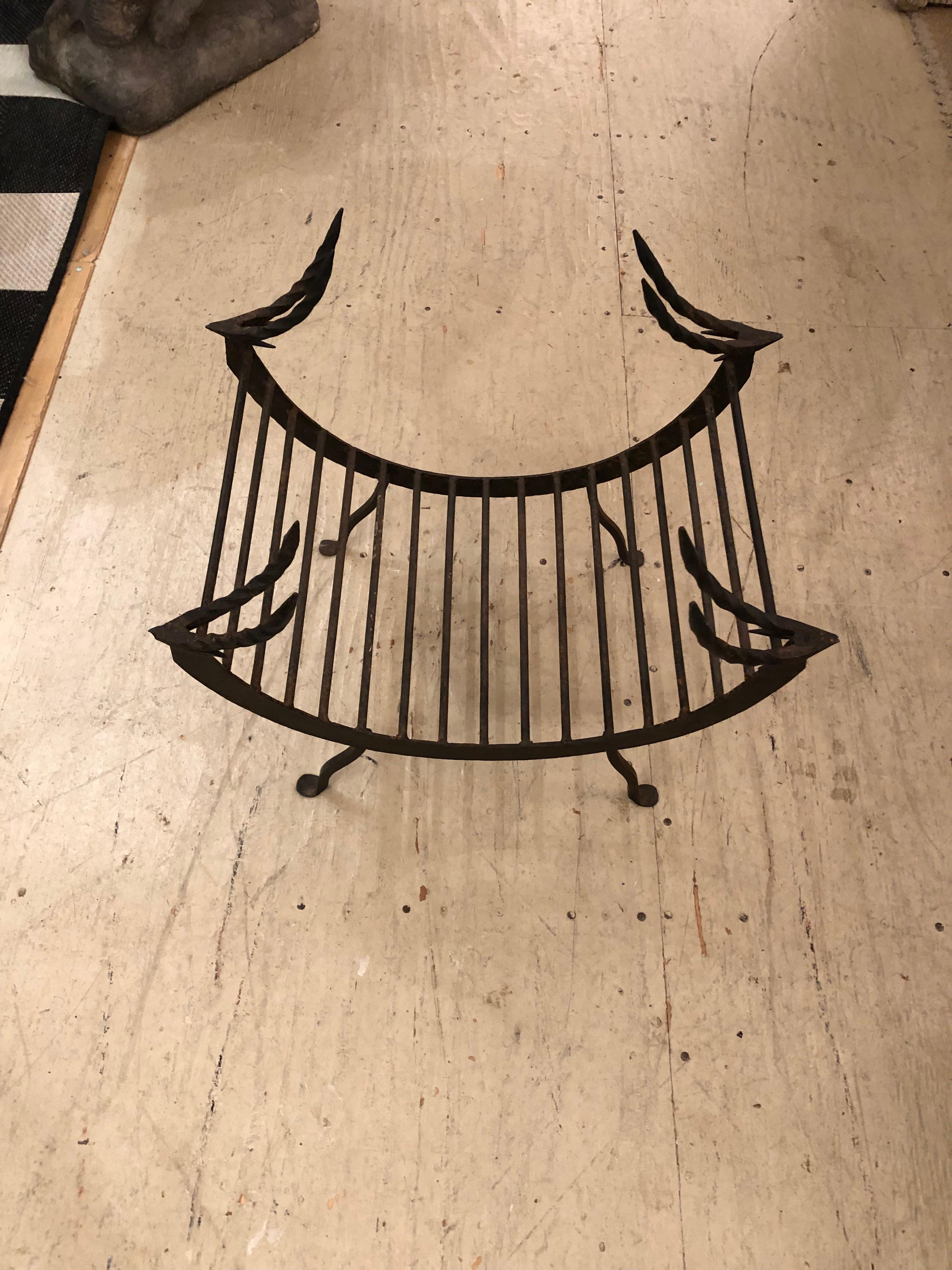 Marvelously designed hand forged iron fireplace log holder having curved shape on legs and stylized deer or ibex in each top corner.