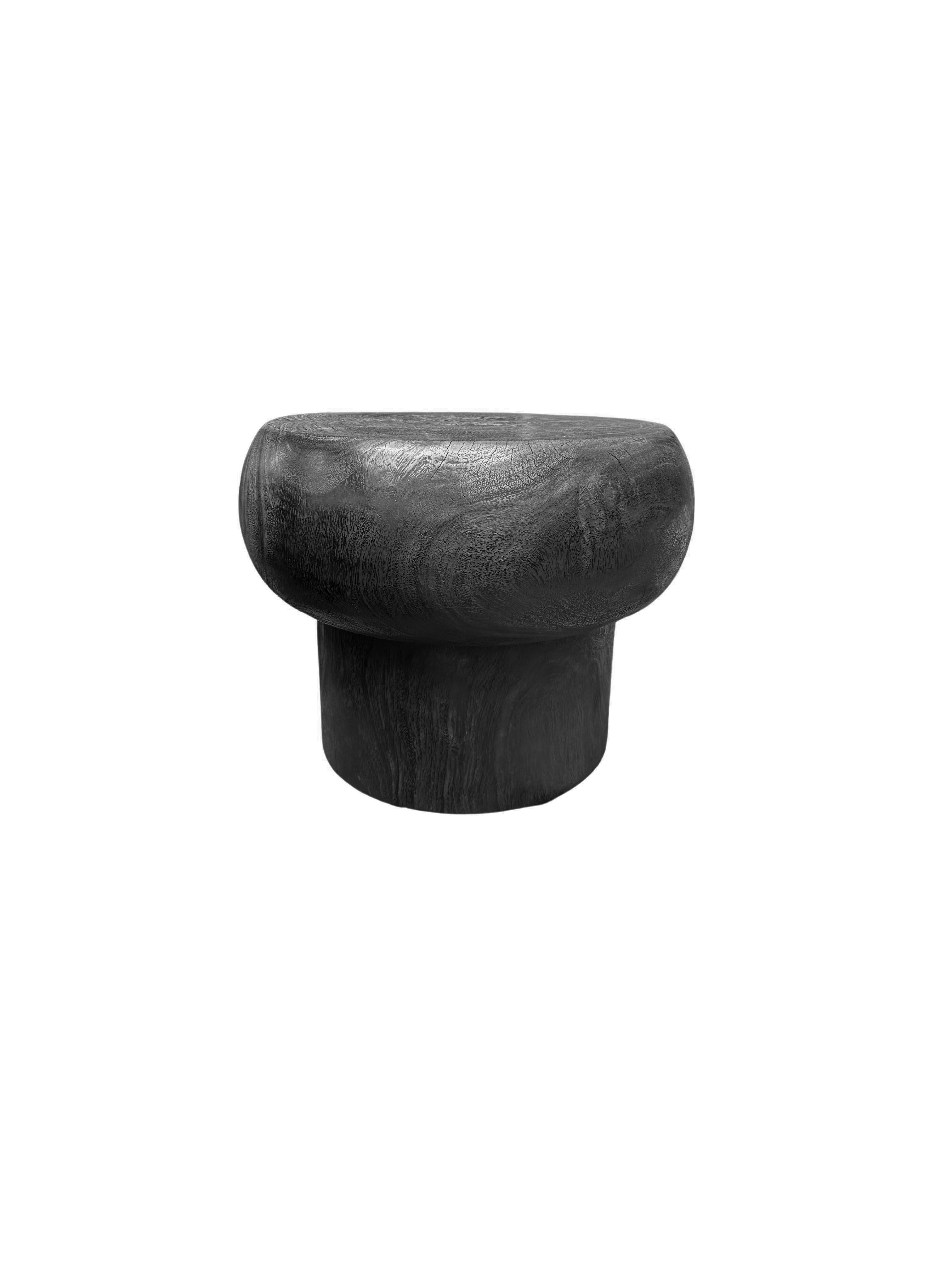 Elevate your living space with this sculptural round mango wood side table, a striking blend of artistry and natural beauty. The table features a meticulously hand-carved base that showcases intricate detailing, creating a captivating visual appeal.