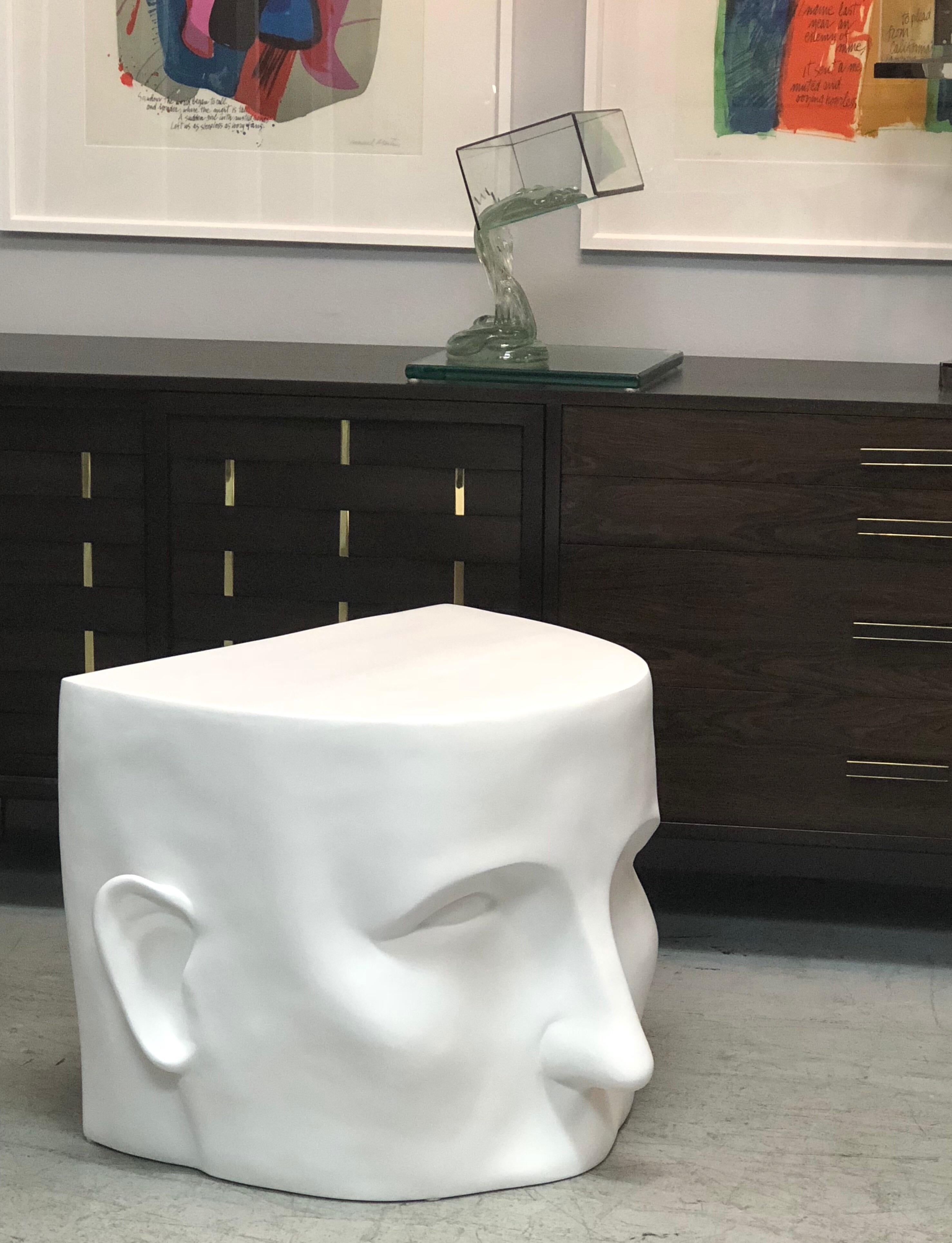 A large architectural table or bench in the form of an stylized partial head. It is resin with a white flat enamel finish, looks like plaster. 2 available.