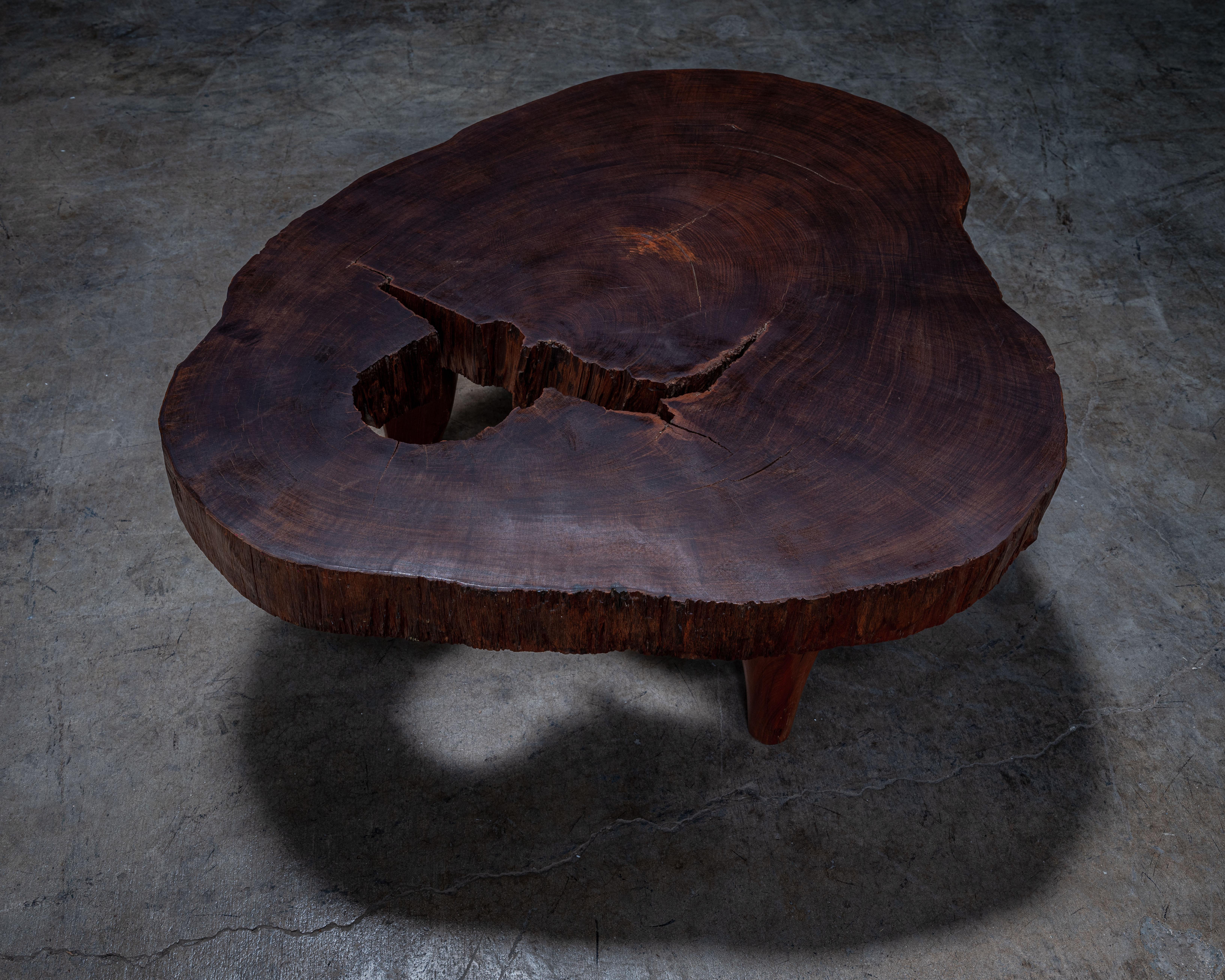 This sculptural coffee table is handcrafted from a single, massive slab of solid Ipe wood, celebrated for its incredible density and deep, chocolate-red hue. The organic, freeform silhouette preserves the raw edges and contours of the original tree,