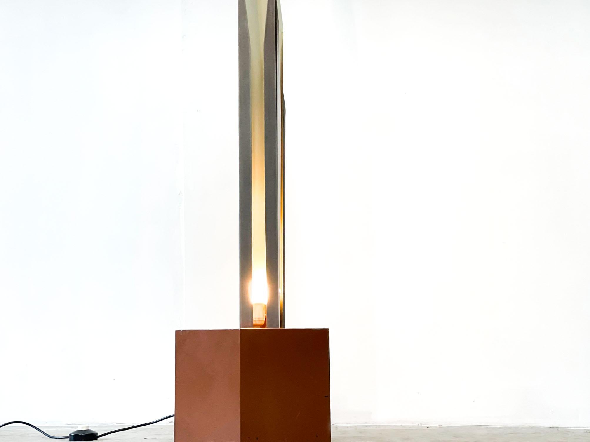 Striking vintage sculptural italian floor lamp. 

Its consists of three long aluminum 'shades' with a white metal finish inside to create a nice and soft light ambiance.

These metal shapes are mounted on a wooden kubus. 

1970s - Italy

Very good