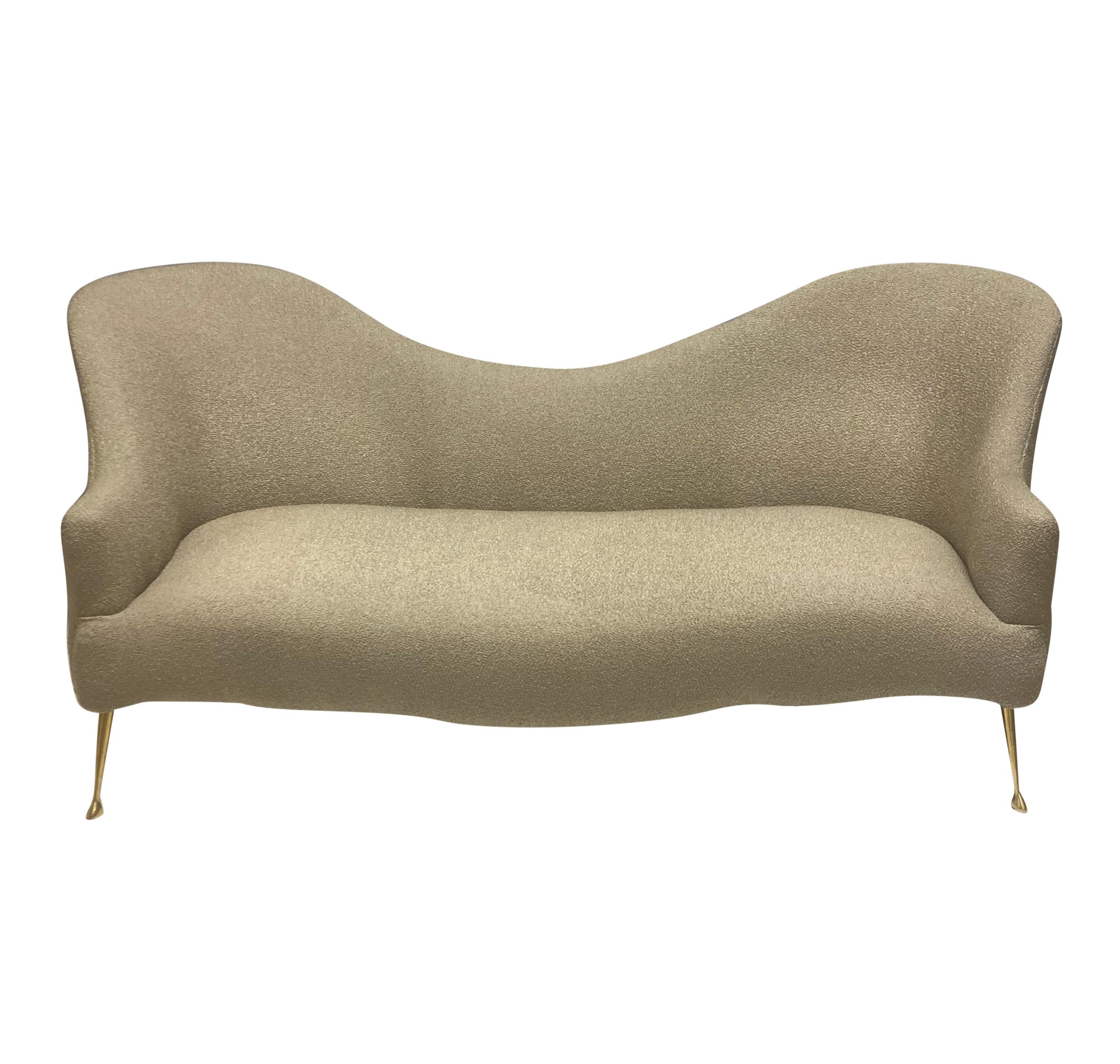 An Italian mid-century sofa of sculptural form, on brass legs and newly upholstered in a stone coloured wool boucle.
