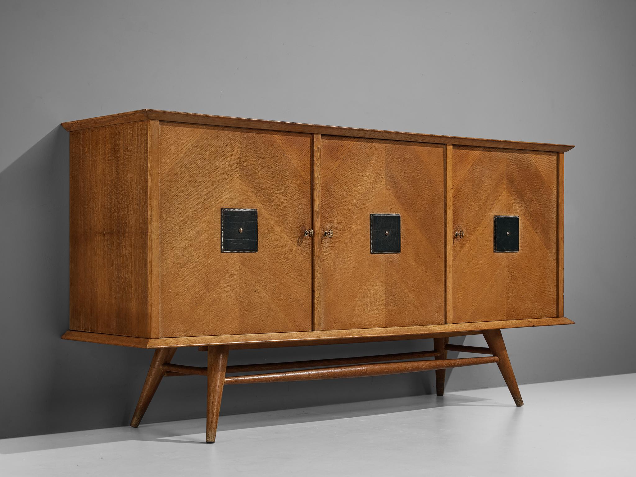 Sideboard, oak, brass, leather, Italy, 1960s

Sculptural Italian sideboard with geometric detailing. The sideboard is placed on sleek, tapered legs that give the design some openness. These legs add to the sculptural character of the sideboard and