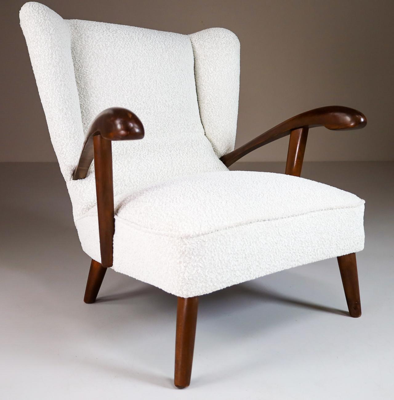 Sculptural wing chair in solid walnut and Re-upholstered bouclé wool fabric, Italy 1950s. The grain of the wood is nicely visible, especially on the elegant sculpted armrests. This armchair - lounge chair would make an eye-catching addition to any