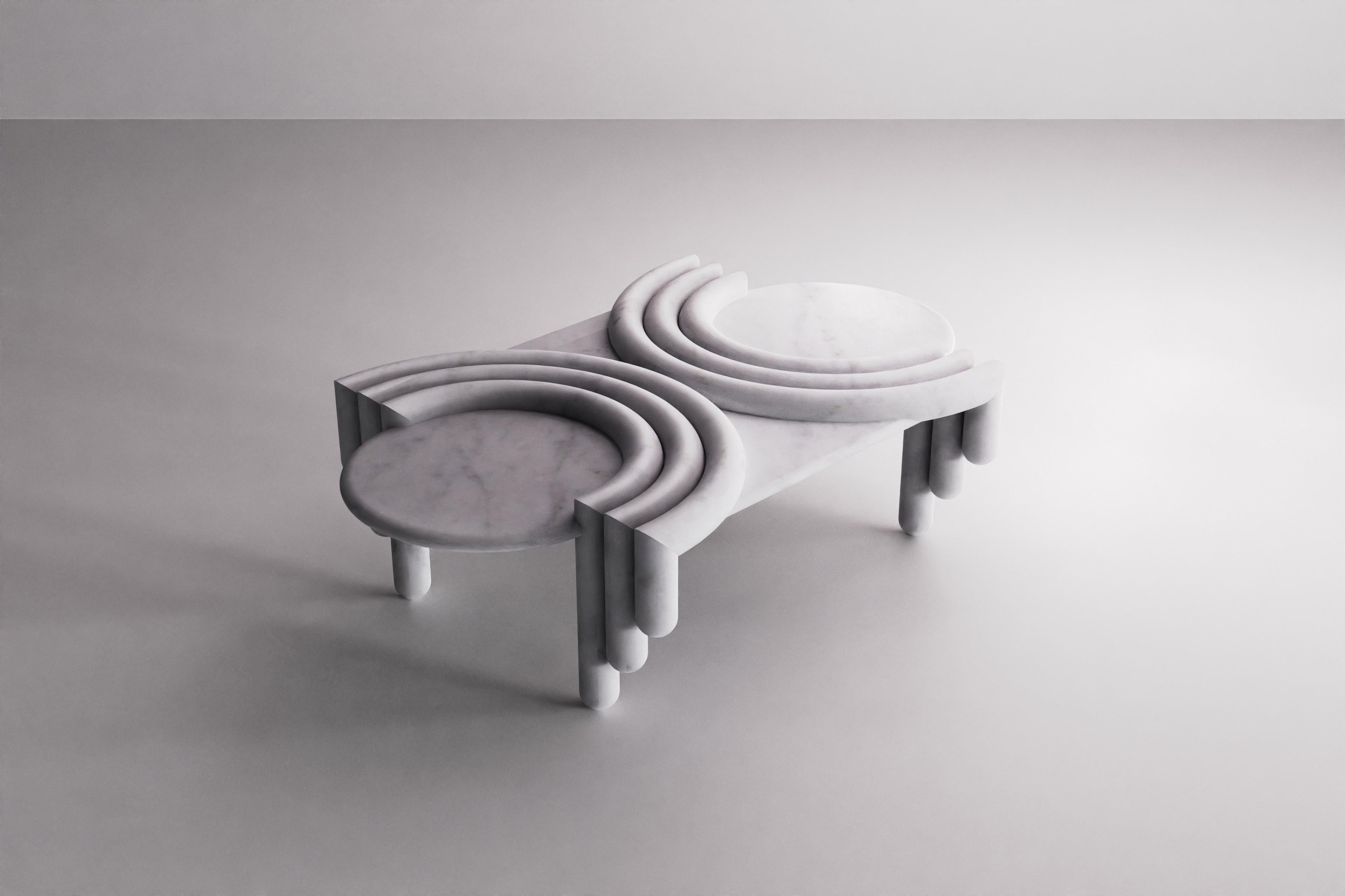 La table basse en marbre Kipferl a pour pieds des bâtons sculpturaux ruisselants qui rappellent des doigts d'éponge. Ceux-ci s'incurvent pour former le plateau de la table, un croissant semi-circulaire composé de trois rangées de profils arrondis