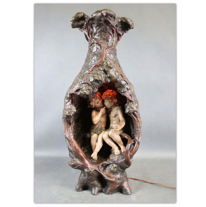 This glazed and hand-painted ceramic lighted sculpture (likely faience or gesso) by Luca Madrassi (1848-1918) depicts cherubs (putti) in a grotto, and is lit in the interior from a bulb mounted at top.  Signed.  In fine working condition and ready