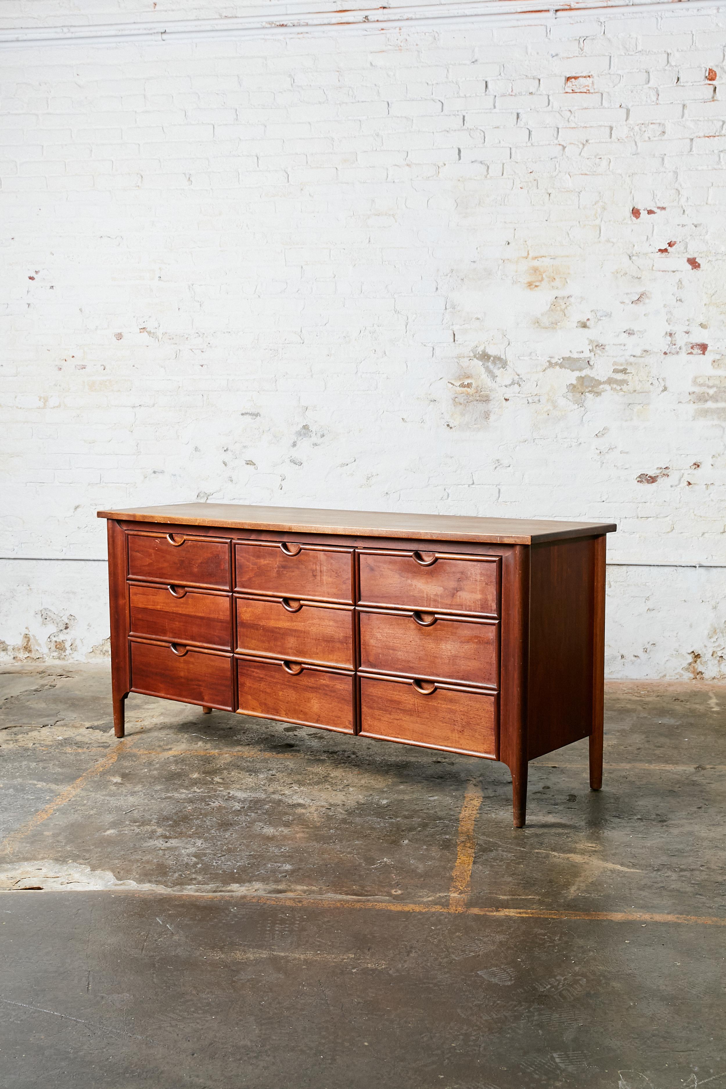 Mid-Century Modern exposed sculpted legs dresser credenza with nine drawers. Natural finish in deep brown color.