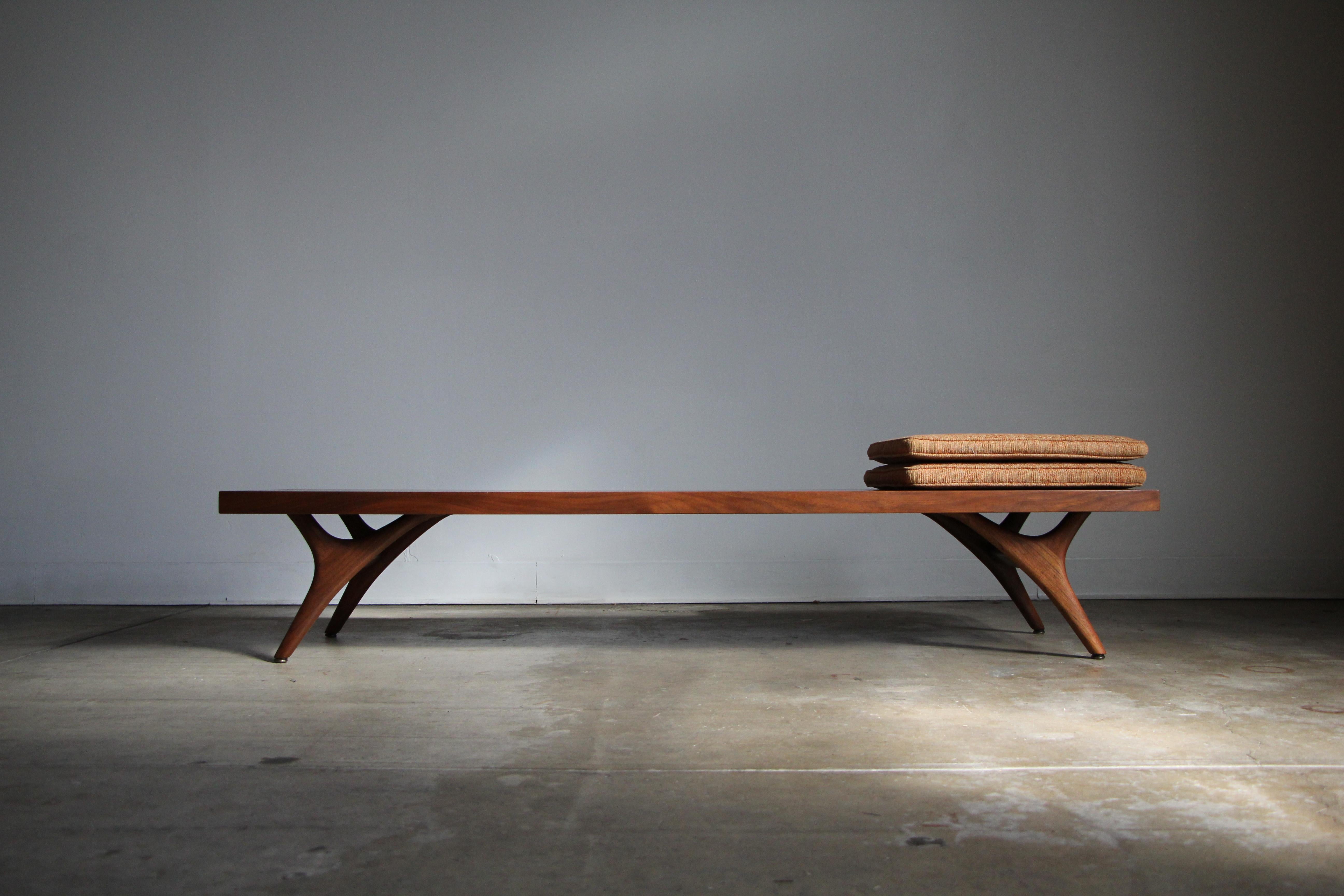 This rare low bench or coffee table was likely designed by Vladimir Kagan for Grosfeld House in the 1950s, though it is unmarked. The bench consists of a solid walnut top and four beautifully sculpted walnut legs, a hallmark detail of Kagan's early