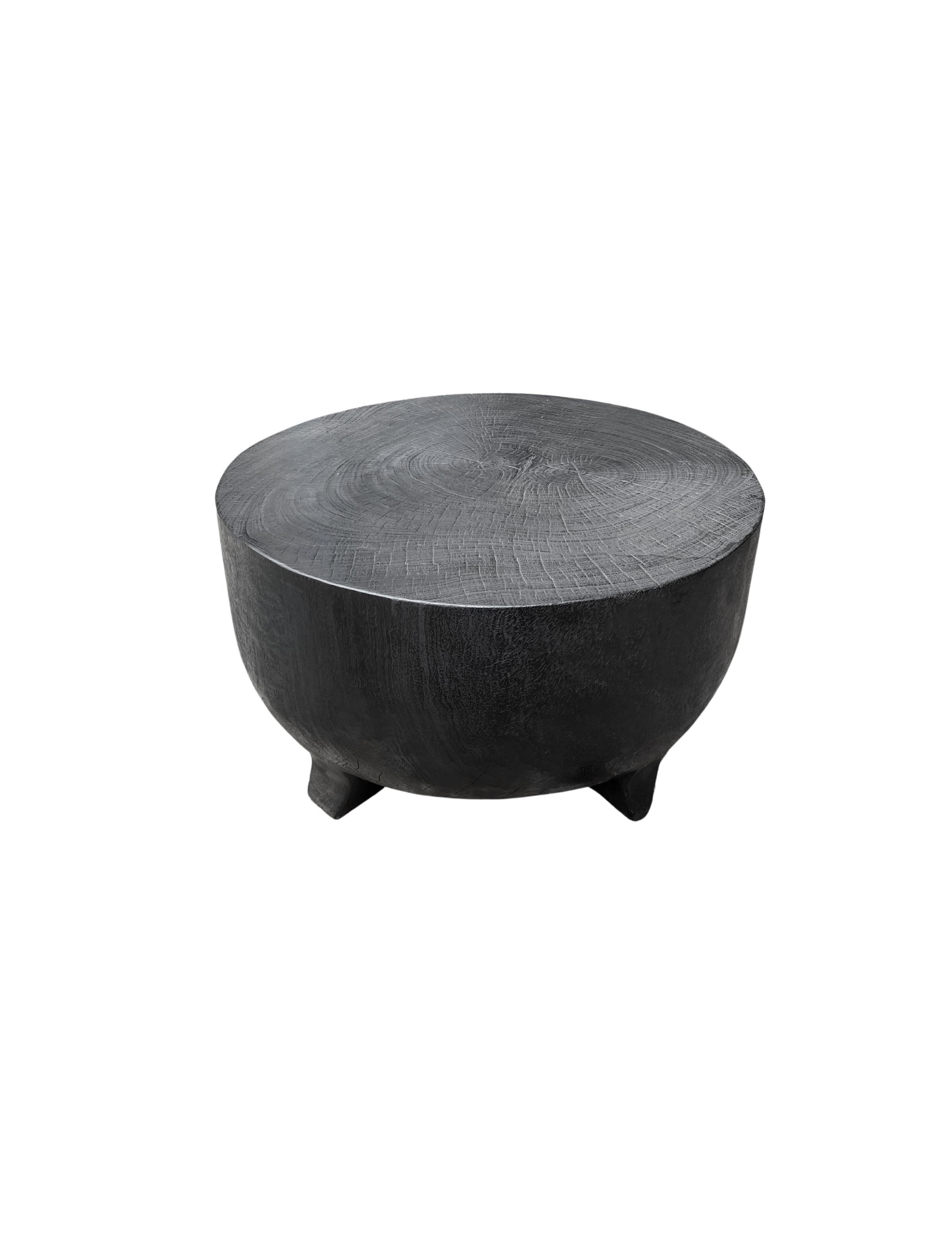 A wonderfully sculptural round side table elevated on four, low and curved legs. Its rich black pigment was achieved through burning the wood three times. Its neutral pigment and subtle wood texture makes it perfect for any space. A uniquely
